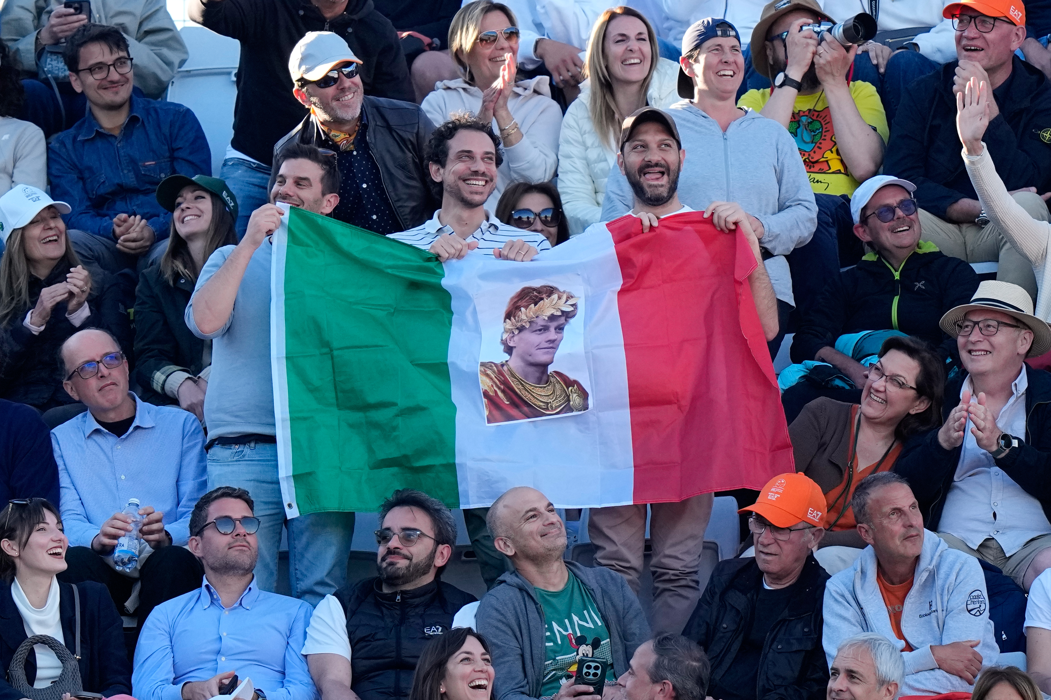 Fans of Jannik Sinner, of Italy, hold an Italian flag with his picture during his final match against Casper Ruud, of Norway, at the Italian Open tennis tournament, in Rome, Sunday, May 17, 2026. (AP Photo/Alessandra Tarantino)