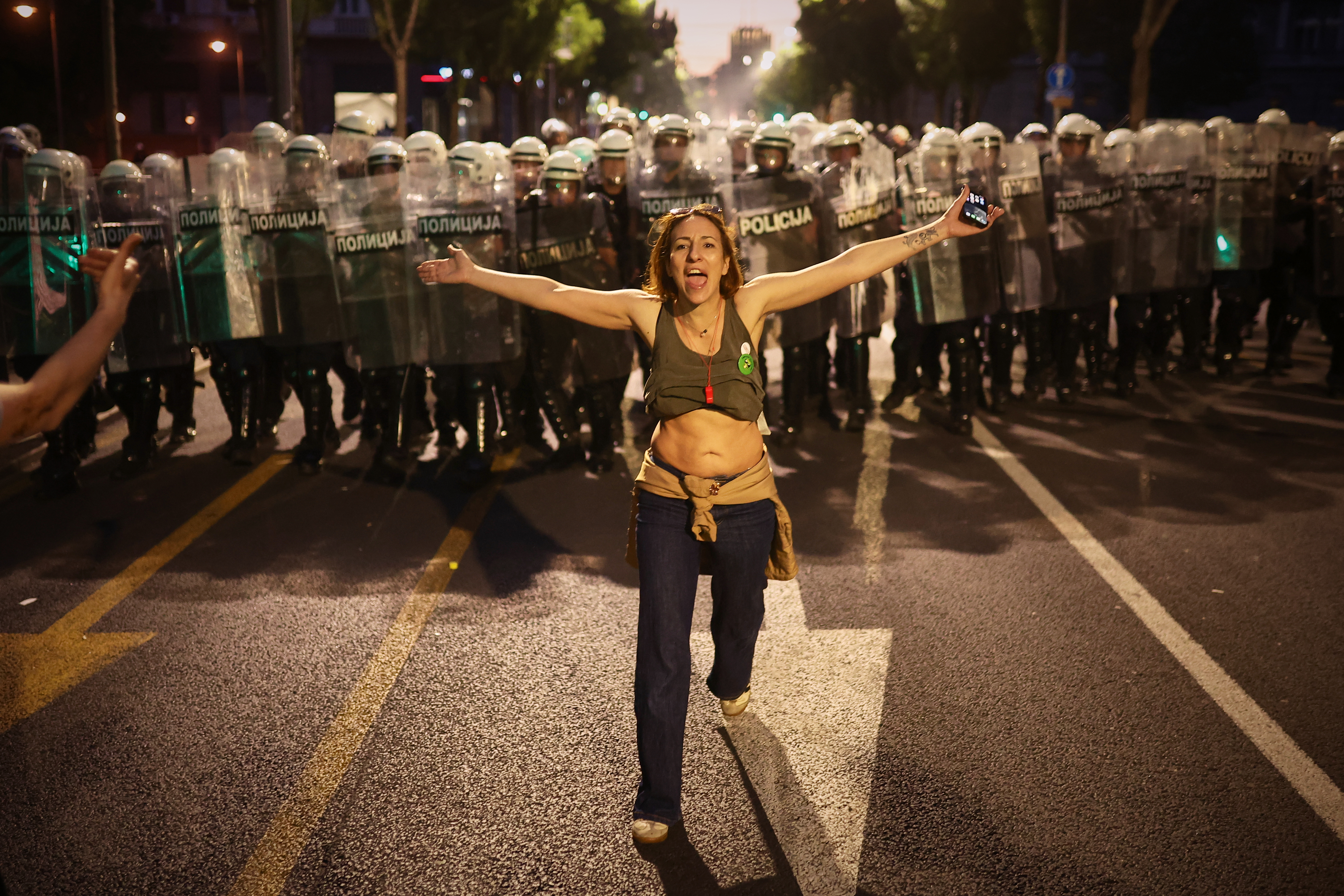 A woman who said she is pregnant walks in front of riot policemen as they prepare to disperse anti-government protesters during a rally led by Serbia's protesting university students who are pushing for major political changes in the Balkan country run by President Aleksandar Vucic, in Belgrade, Serbia, Saturday, May. 23, 2026. (AP Photo/Armin Durgut)