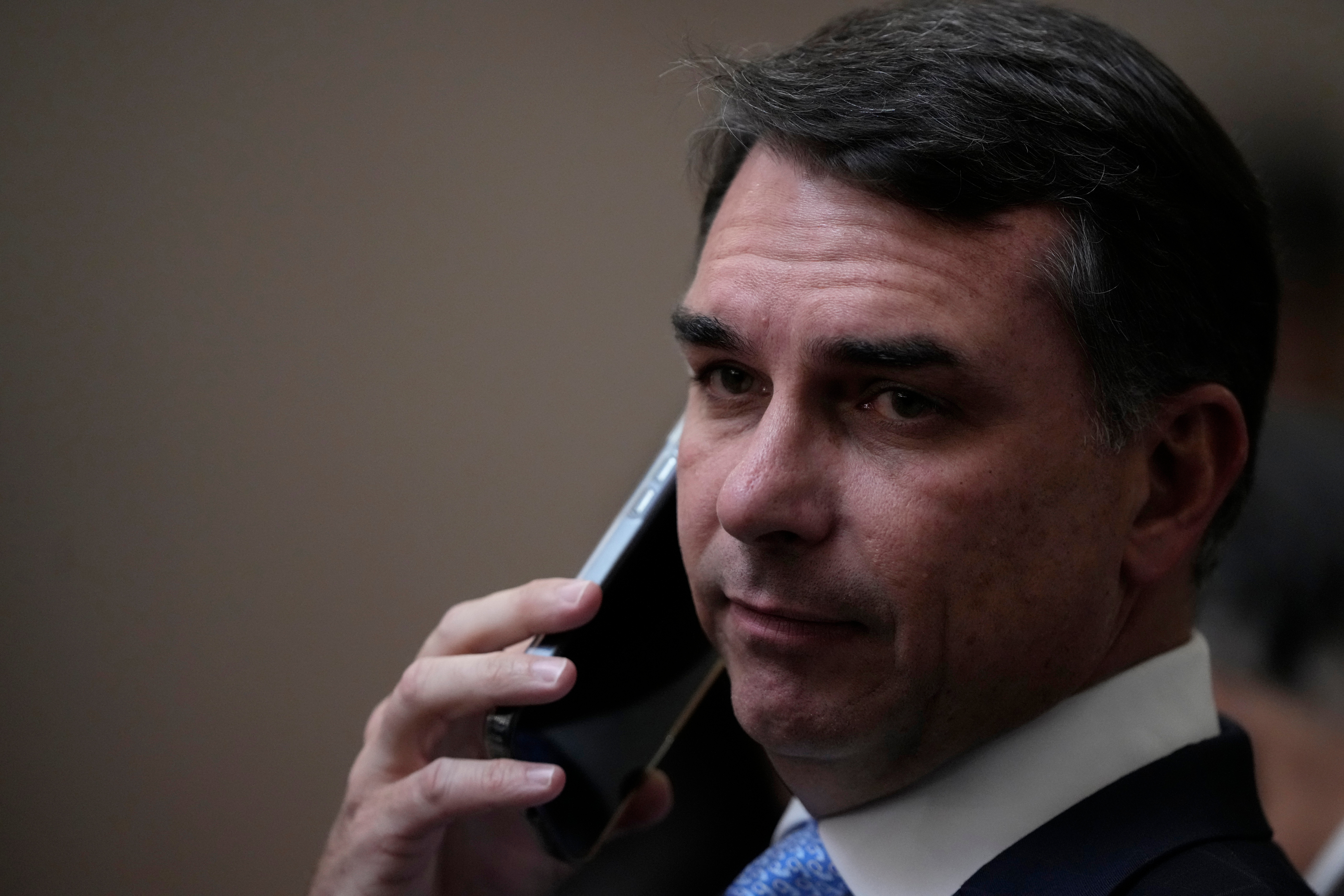Sen. Flavio Bolsonaro, son of former Brazilian President Jair Bolsonaro, talks on the phone as he arrives for the swearing-in ceremony for justices Nunes Marques and Andre Mendonca as president and vice president of Brazil's Superior Electoral Court in Brasilia, Brazil, Tuesday, May 12, 2026. (AP Photo/Eraldo Peres)