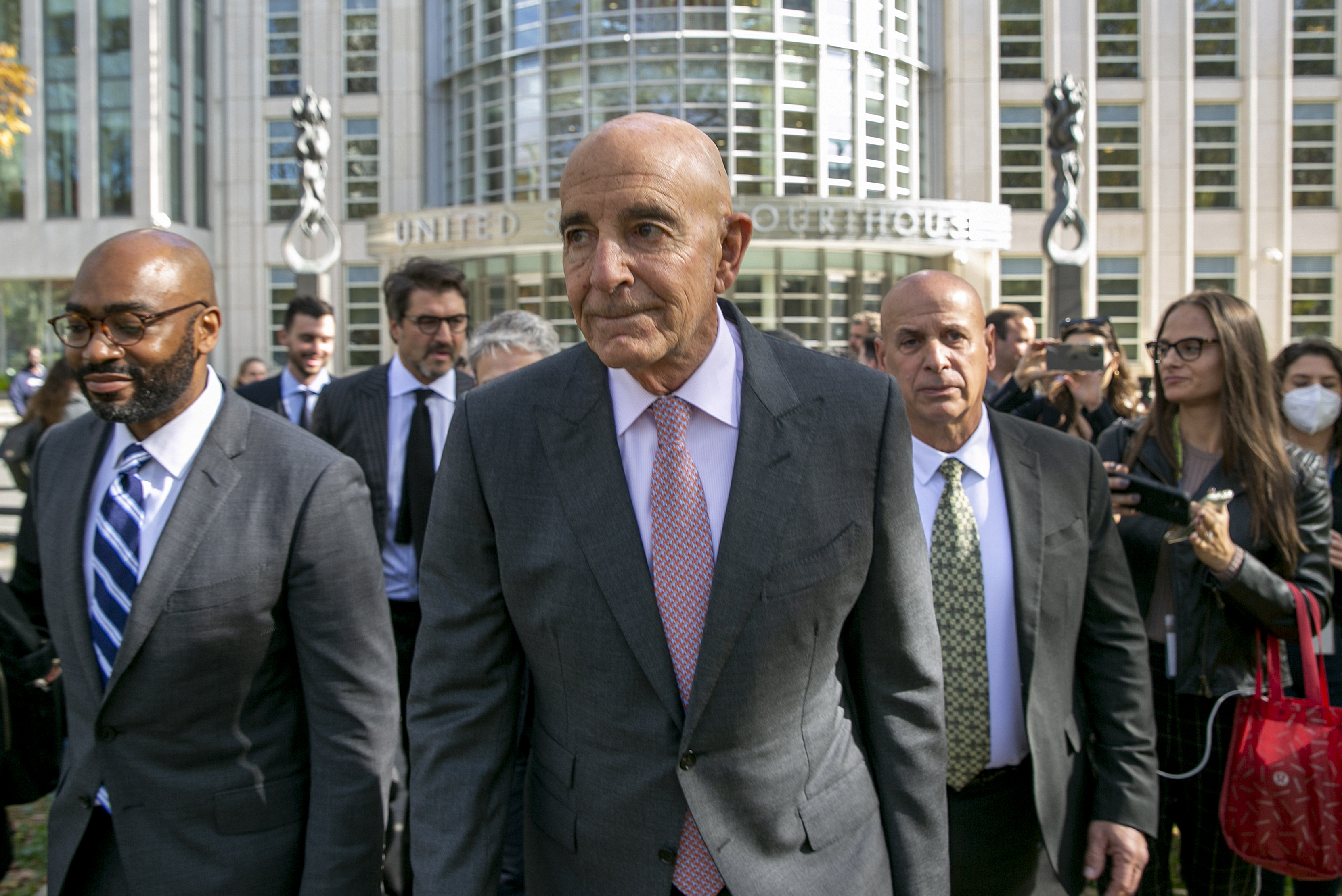 Tom Barrack, centre, with a group of other people leaving a building.