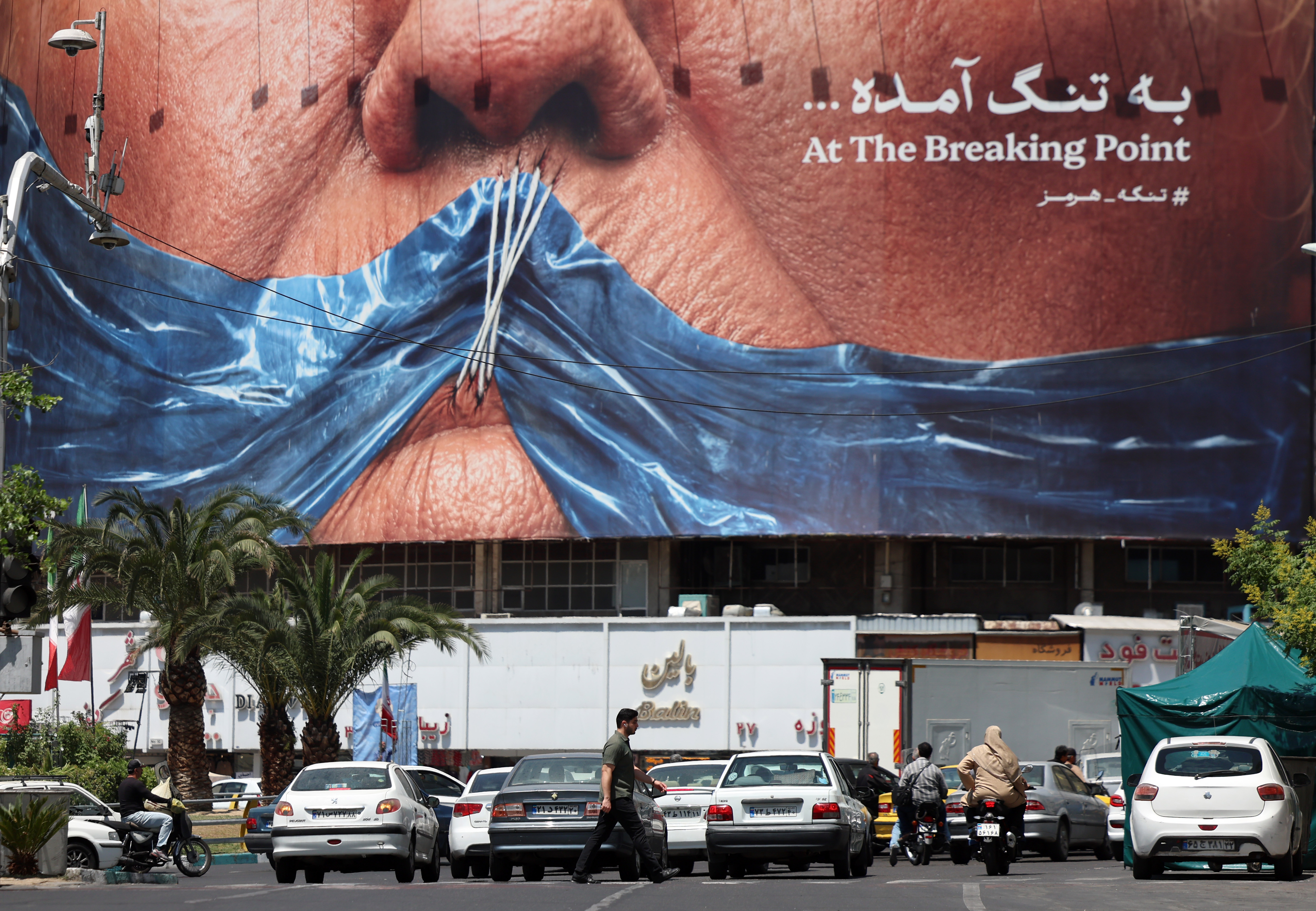epa12980238 Iranians walk in front of a large anti-US billboard featuring US President Donald Trump and the Strait of Hormuz at Valiasr Square in Tehran, Iran, 21 May 2026. Tensions between the US and Iran continue as a deal has not been reached. EPA/ABEDIN TAHERKENAREH