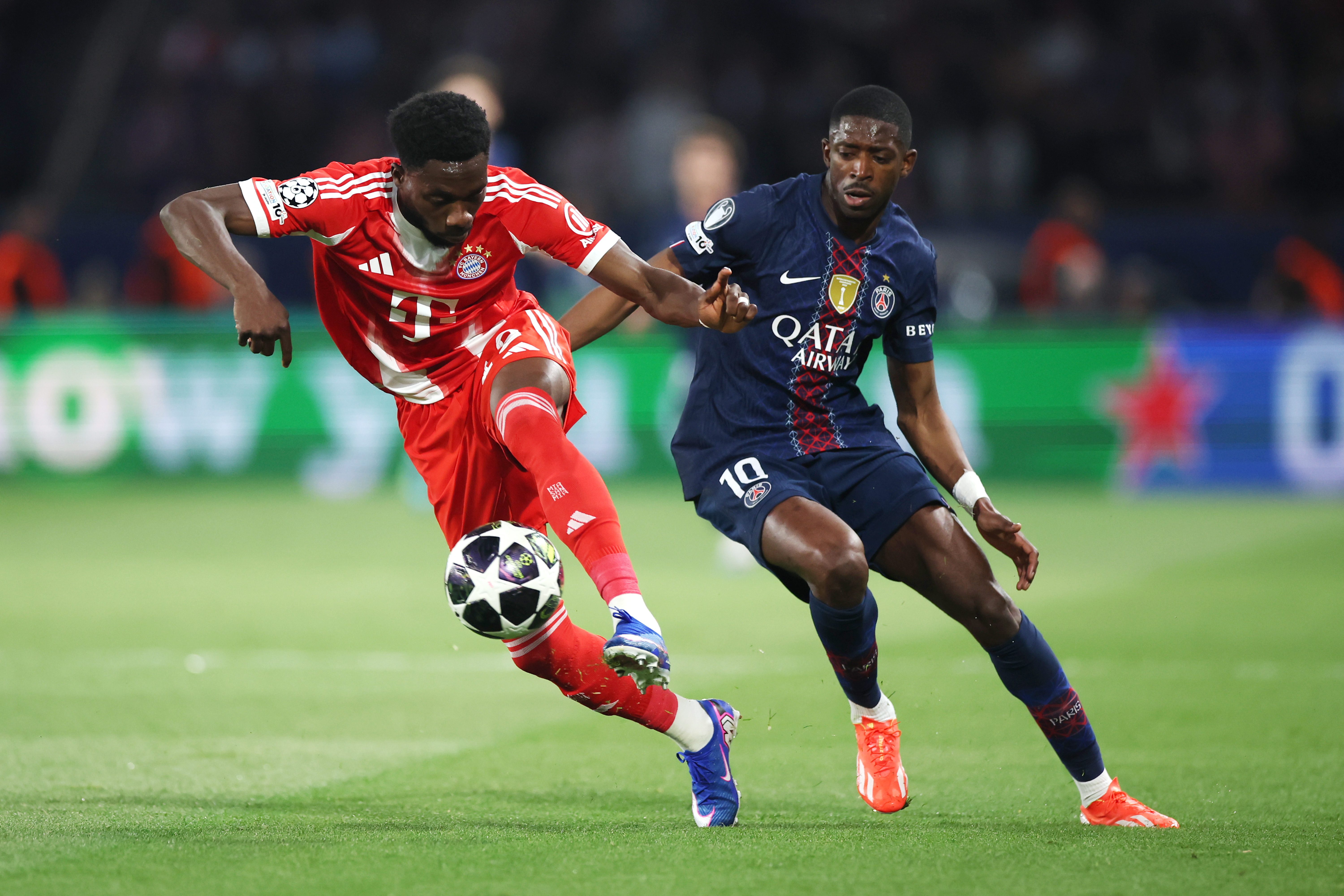 Alphonso Davies of Bayern Muenchen is challenged by Ousmane Dembele of Paris Saint-Germain during a match.