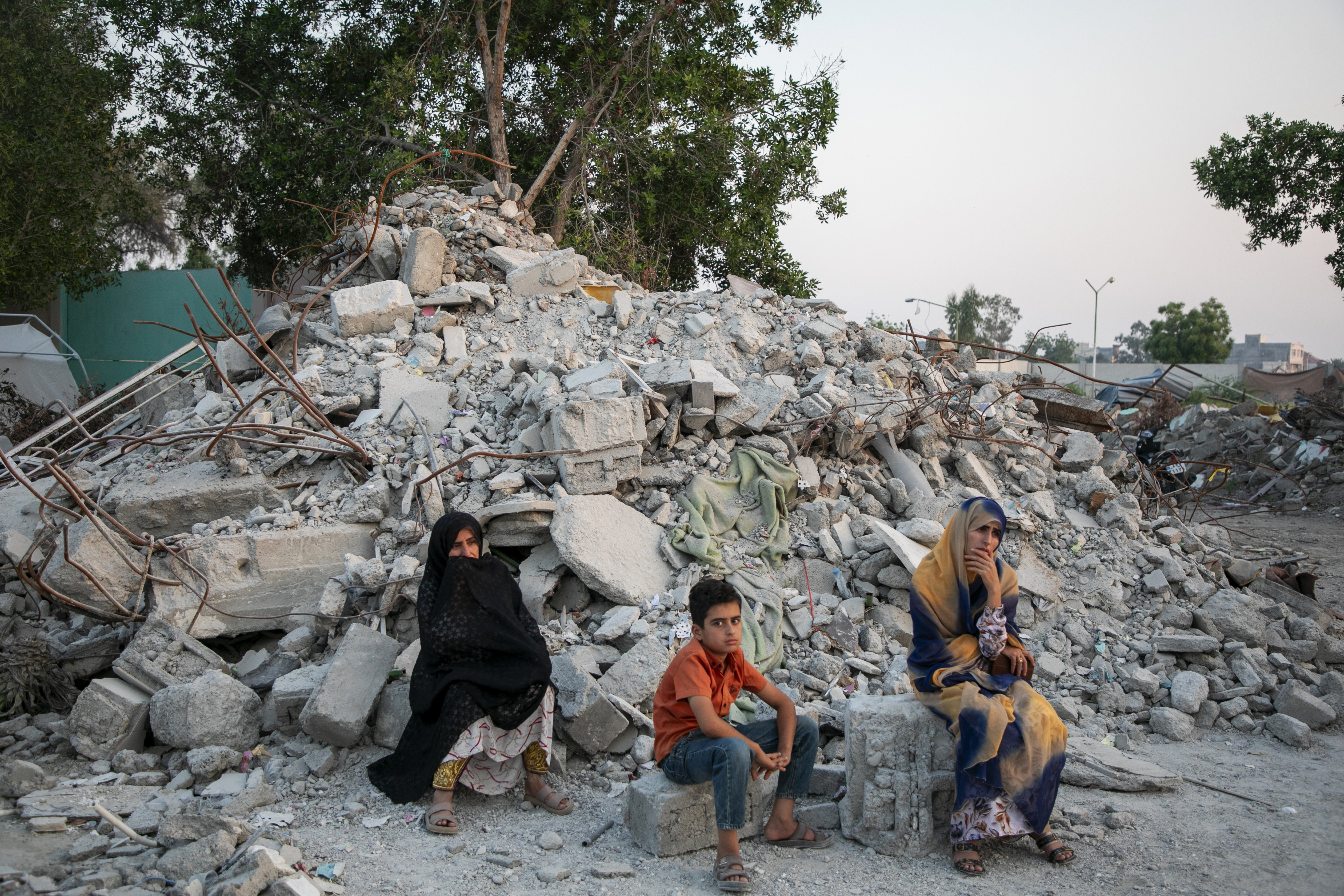 TEHRAN, IRAN - MAY 13: Two women and a child sit in ruins during their visit to Al-Shajara Al-Tayyiba School on May 13, 2026 in Tehran, Iran. On 28 February this year, a US military launched a missile strike that destroyed the all-girls Al-Shajara School in Minab, Iran, killing 175 people, including 47 schoolgirls and 26 teachers and causing global outrage. The attack is the deadliest civilian event of the 2026 Iran war. US investigators later stated American forces hit the school by mistake due to outdated intelligence, as the civilian school sat right next to an Iranian naval base. (Photo by Majid Saeedi/Getty Images)