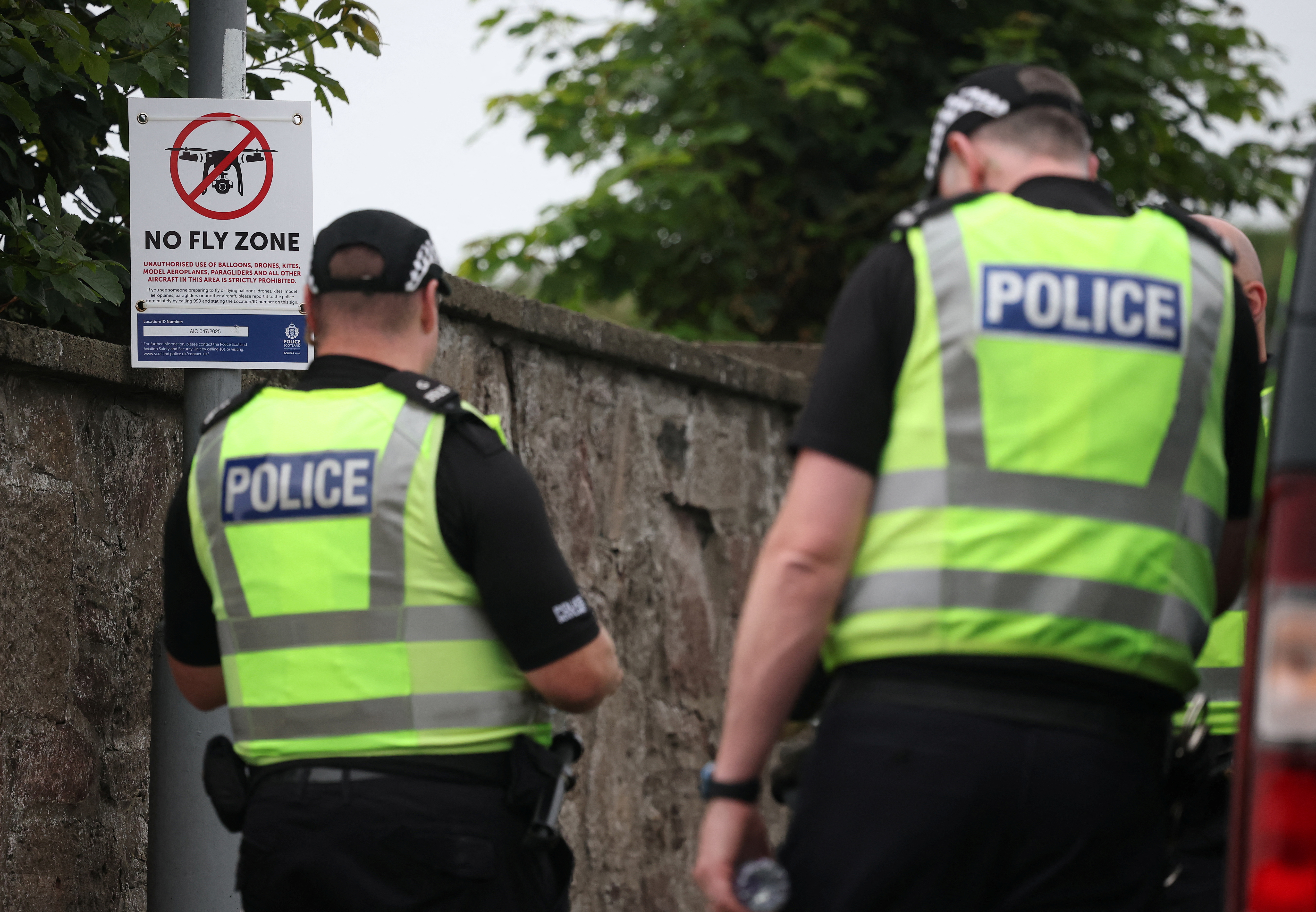 Police officers stand next to a no fly zone sign