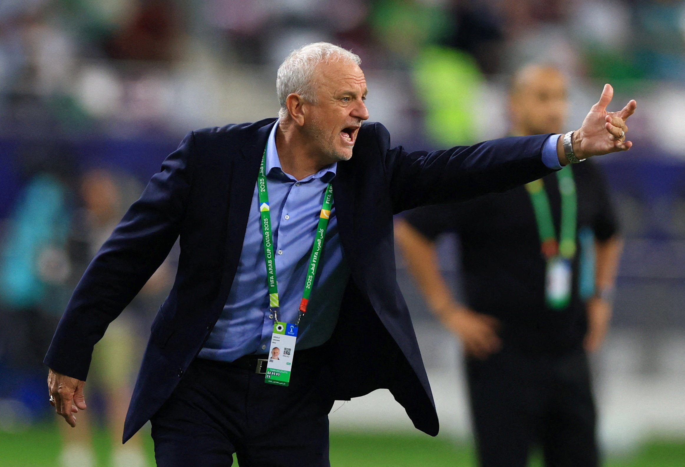 Graham Arnold wearing a suit and pointing