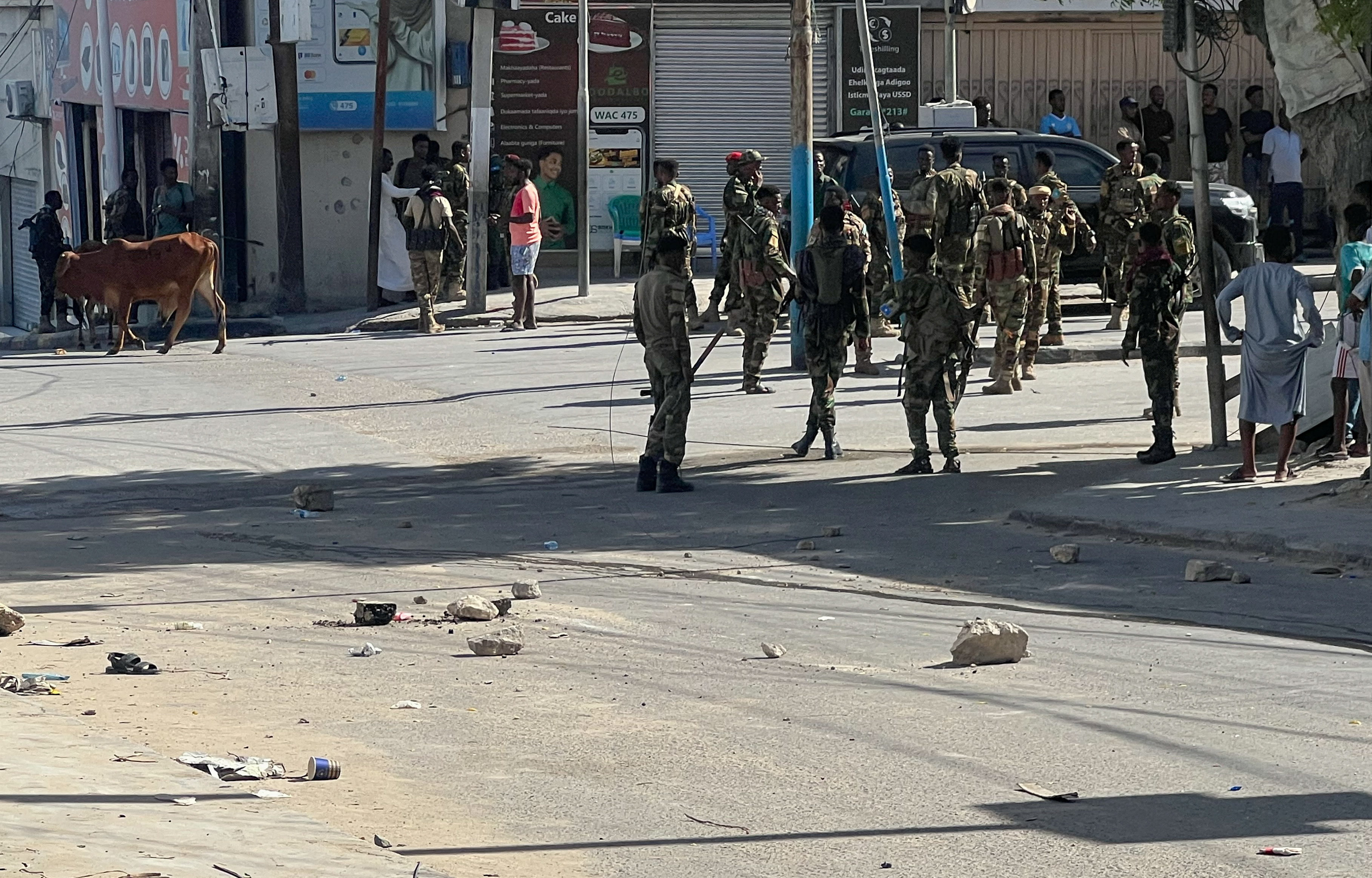 Members of Somali government forces stand among civilians at an intersection before a planned protest against President Hassan Sheikh Mohamud over his decision to remain in office after his term expired last month