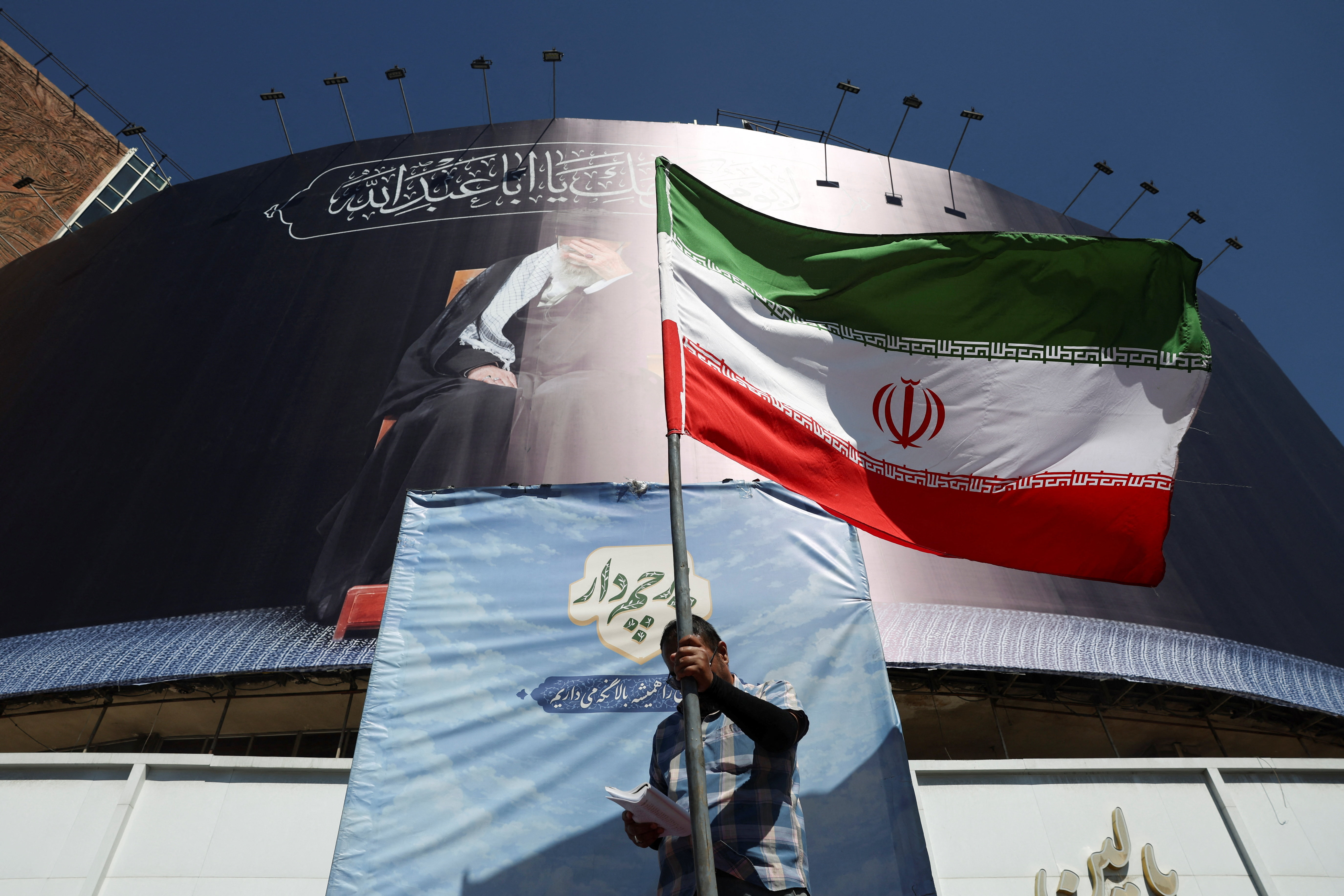 A man holds an Iranian flag on a street, after U.S. and Iranian officials said they had reached a deal to end their war and reopen the Strait of Hormuz