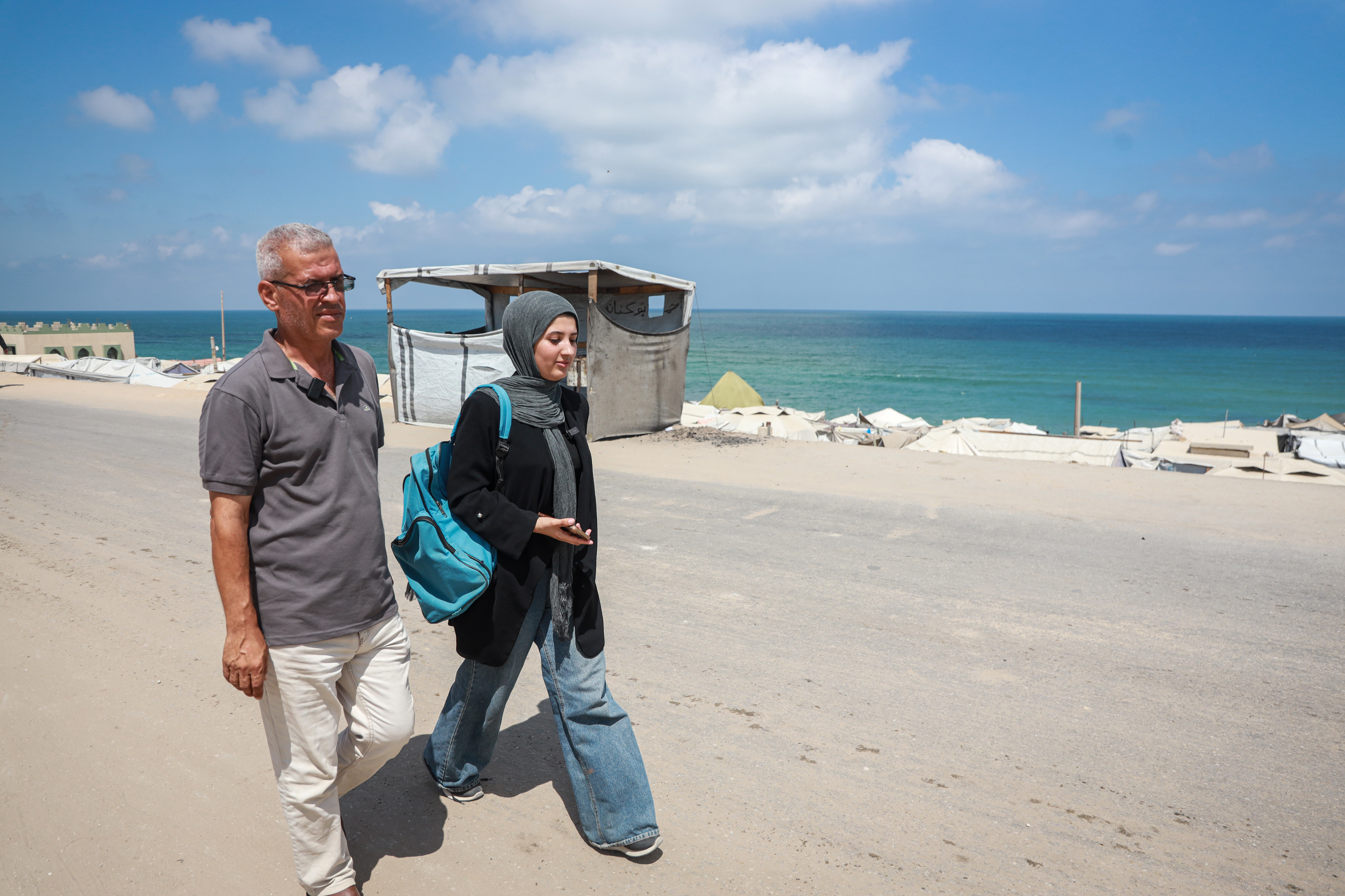 Dana and her father Muhanna walk back home, with the sea in the background