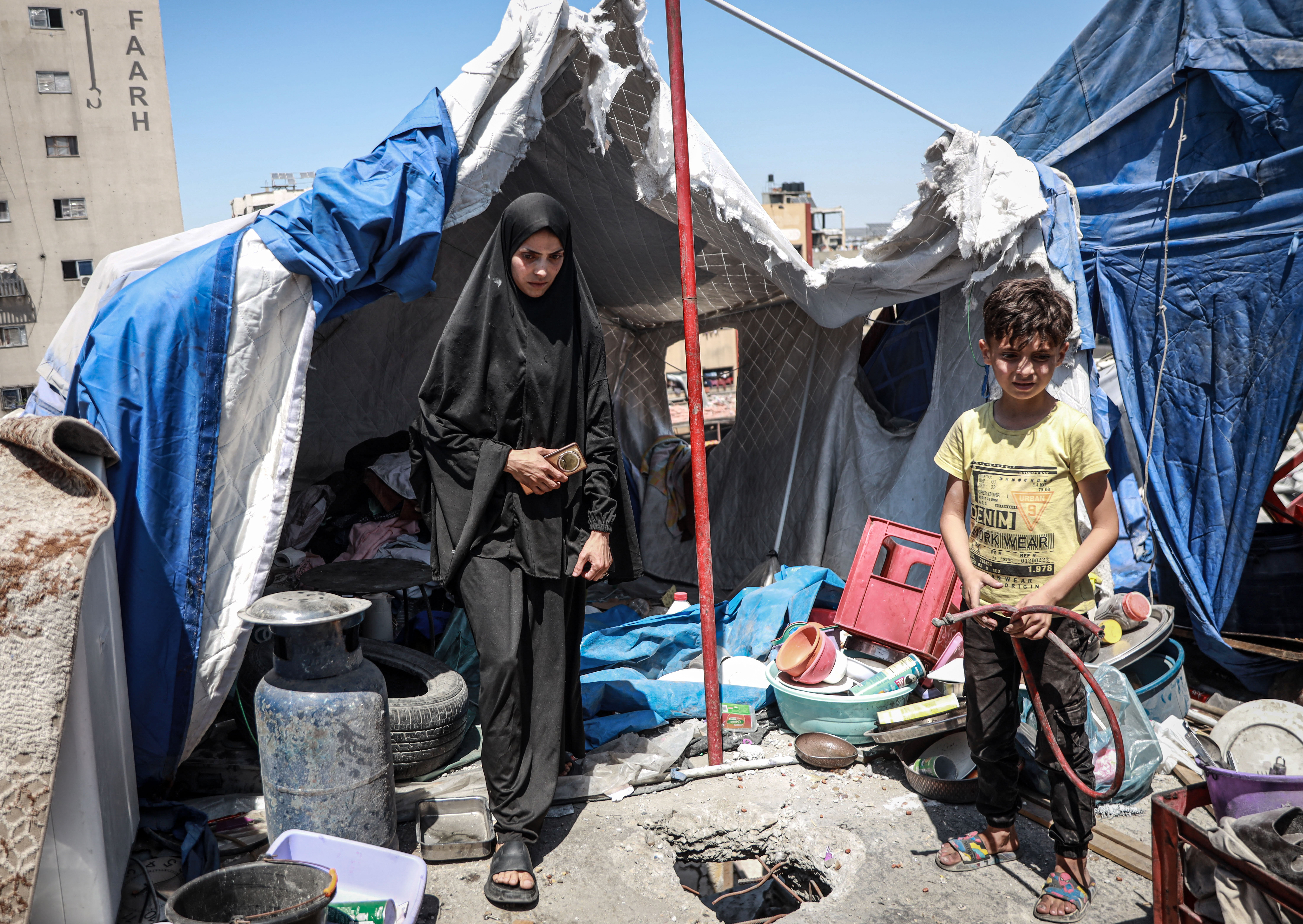 Widad Al-Husari inspects her tent and her belongings that remain after an airstrike hit the building where her family had been sheltering several days ago