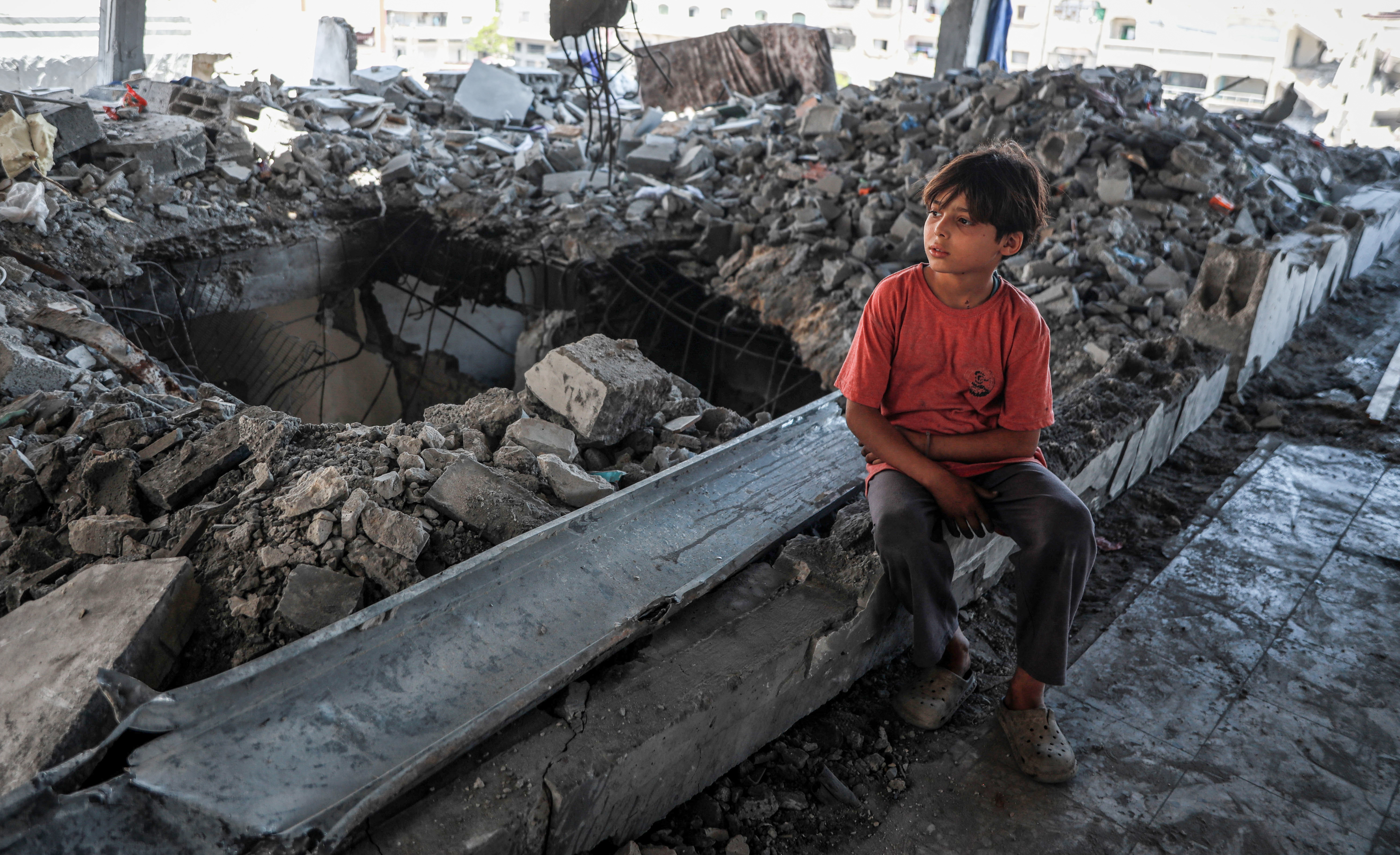A child sits on a huge pile of rubble.