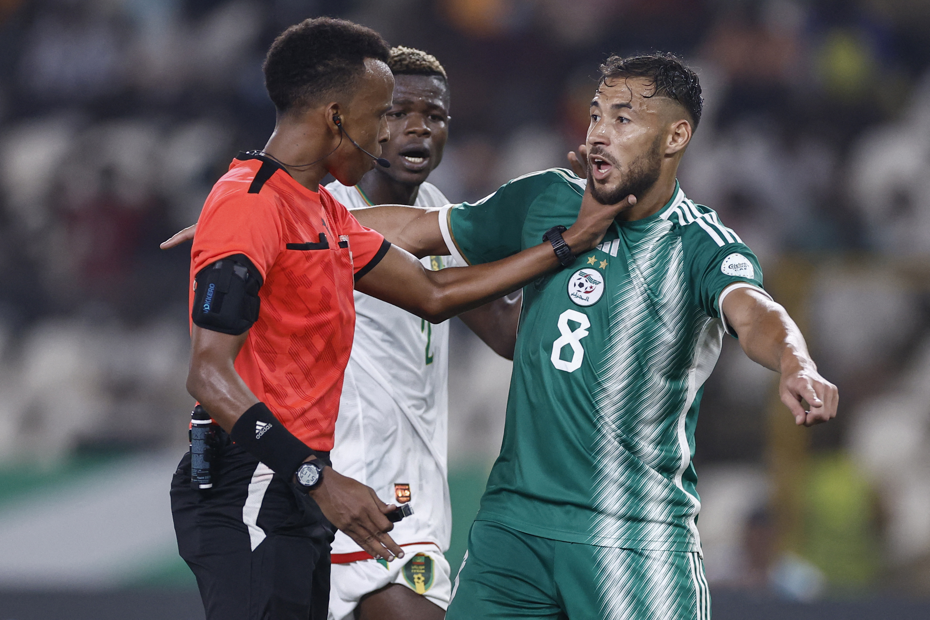 Somalian referee Omar Abdulkadir Artan (L) puts his hand on Algeria's forward #8 Youcef Belaili's neck during the Africa Cup of Nations (CAN) 2024 group D football match between Mauritania and Algeria at Stade de la Paix in Bouake on January 23, 2024. (Photo by KENZO TRIBOUILLARD / AFP)