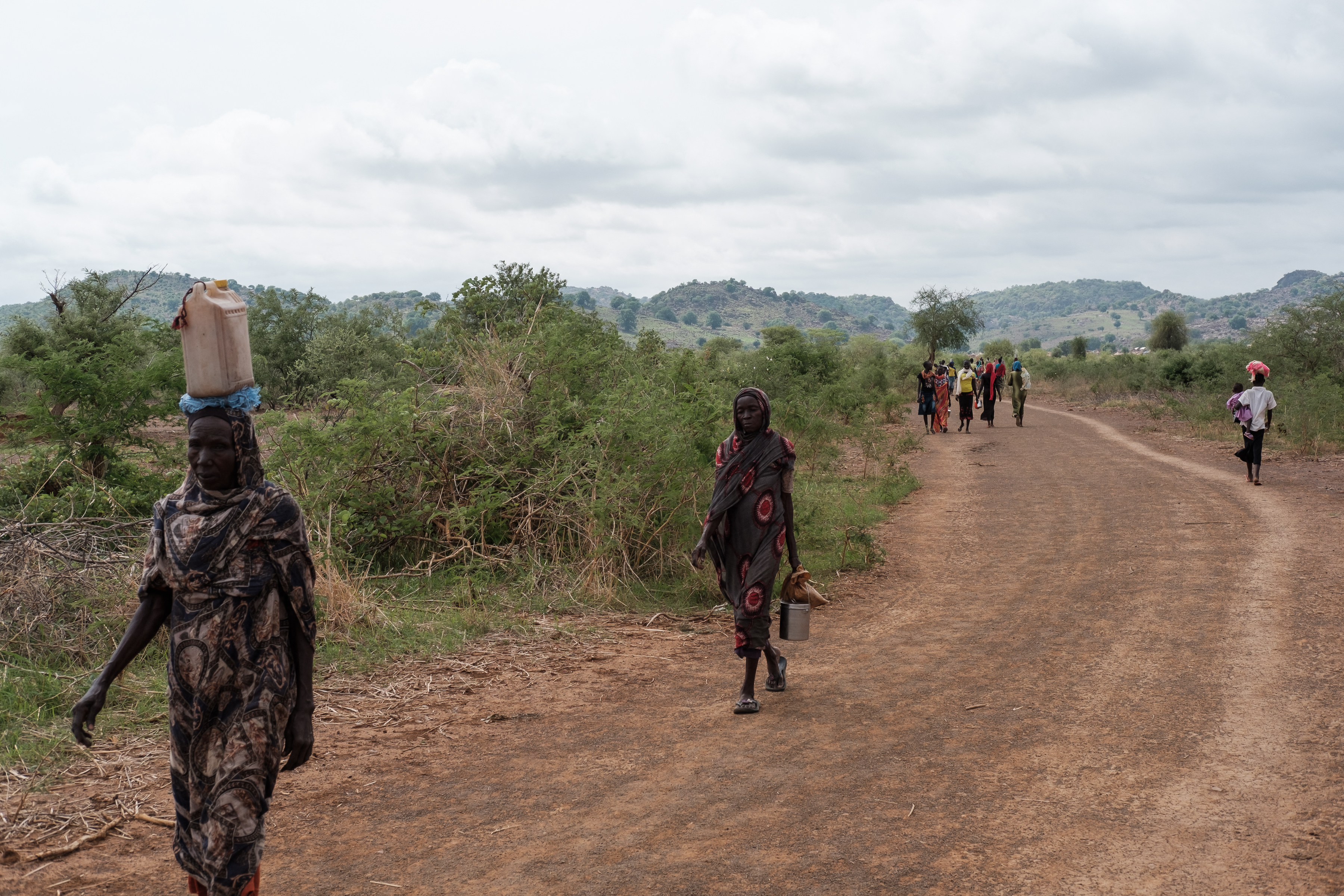 People walk along the road out of the Tiamushro camp for internally displaced persons (IDP) in South Kordofan state, Sudan on June 18, 2024.