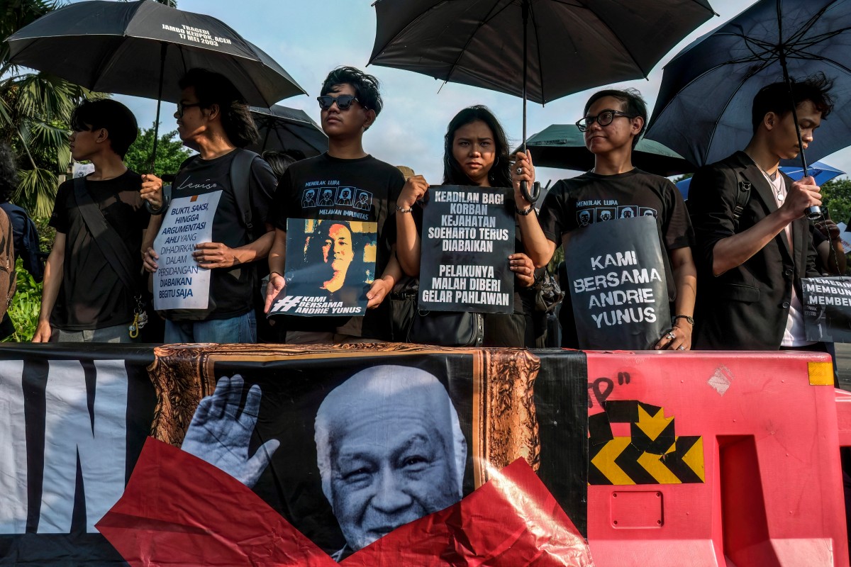Activists hold black umbrellas and posters during a ‘Kamisan’ (every Thursday) protest in front of the Presidential Palace in Jakarta on April 30, 2026, demanding justice for human rights violations and condemning the recent acid attack on Andrie Yunus, the deputy coordinator of the KontraS rights group