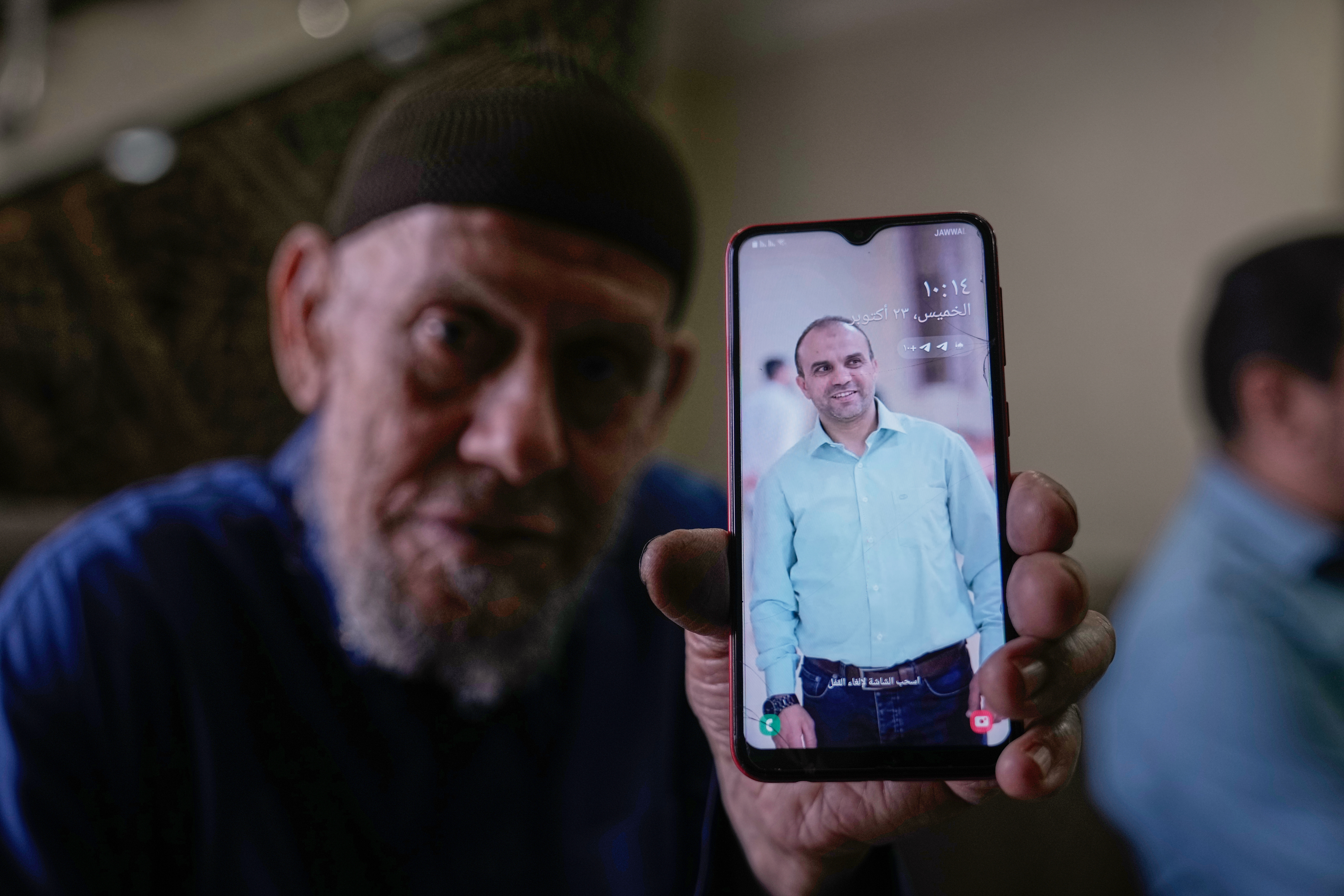 Waleed Husein Ali, shows a picture on a phone of his son, Mohammad, 45, who died in Israeli custody at the Kishon detention centre, as he sits in the family’s living room in the Nur Shams refugee camp near the West Bank town of Tulkarem, on Thursday, October 23, 2025