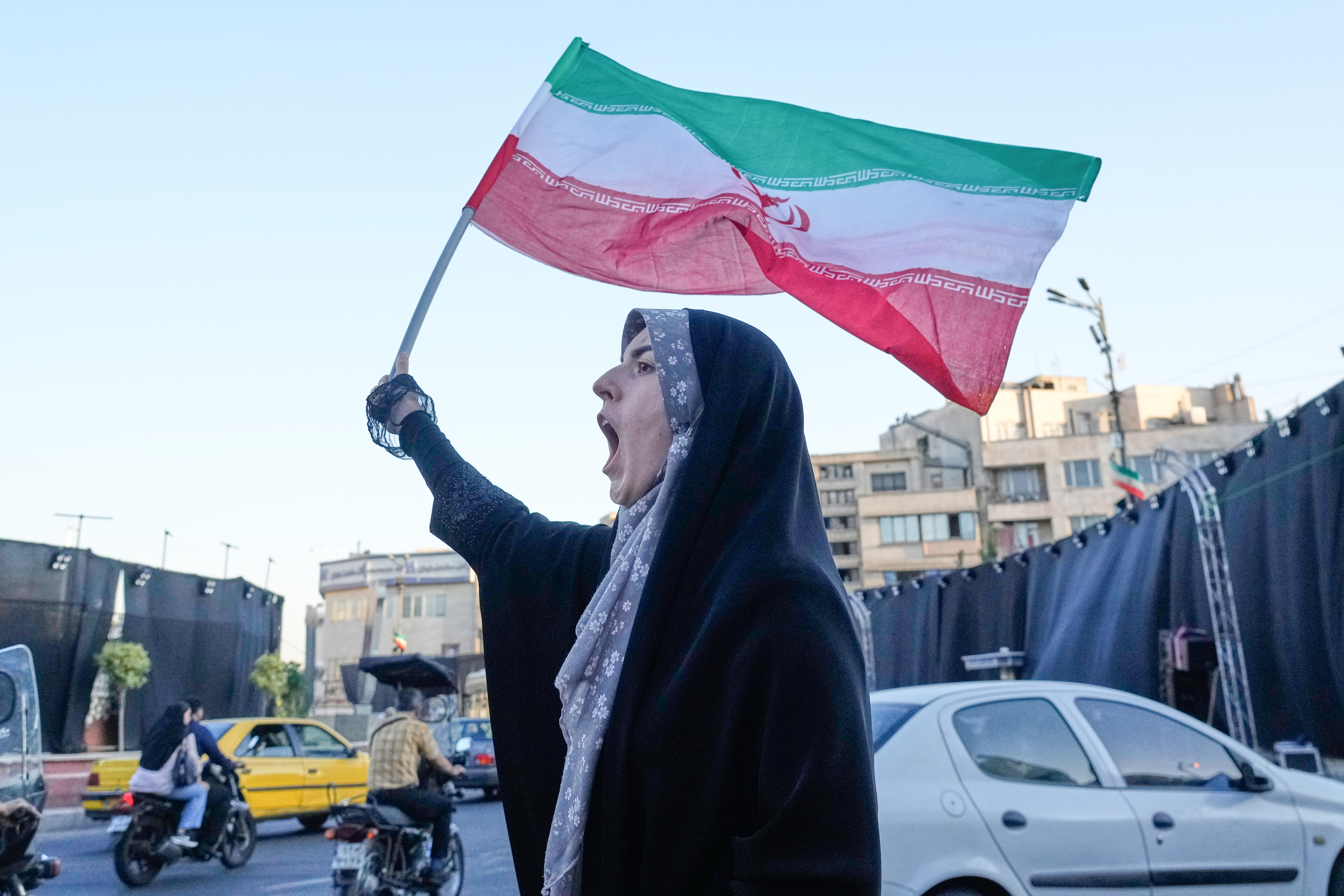 A woman waves an Iranian flags as she chants slogans against Iran and U.S. talks at the Islamic Revolution square in Tehran