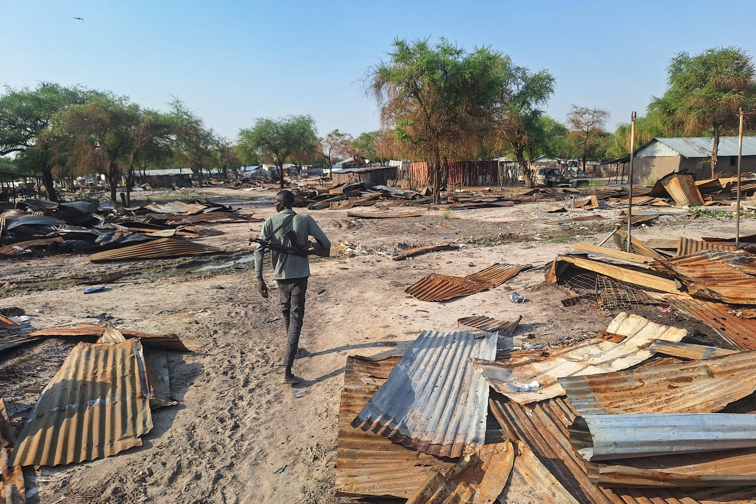 A man walks through a destroyed village.