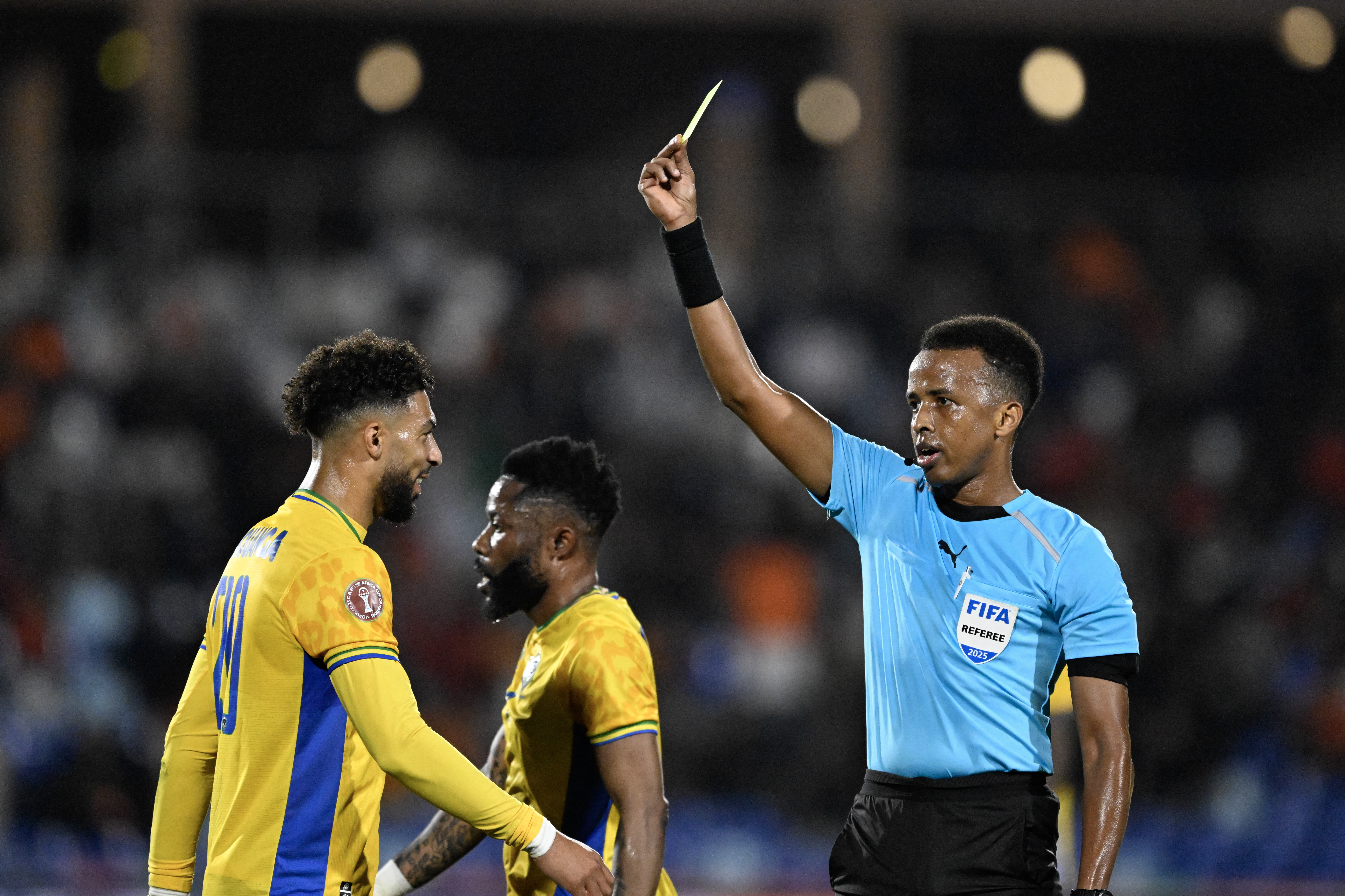 (FILES) Gabon's forward #20 Denis Bouanga is shown the yellow card by Somali referee Omar Abdulkadir Artan during the Africa Cup of Nations (CAN) Group F football match between Gabon and Ivory Coast at the Grand Stadium in Marrakech on December 31, 2025.