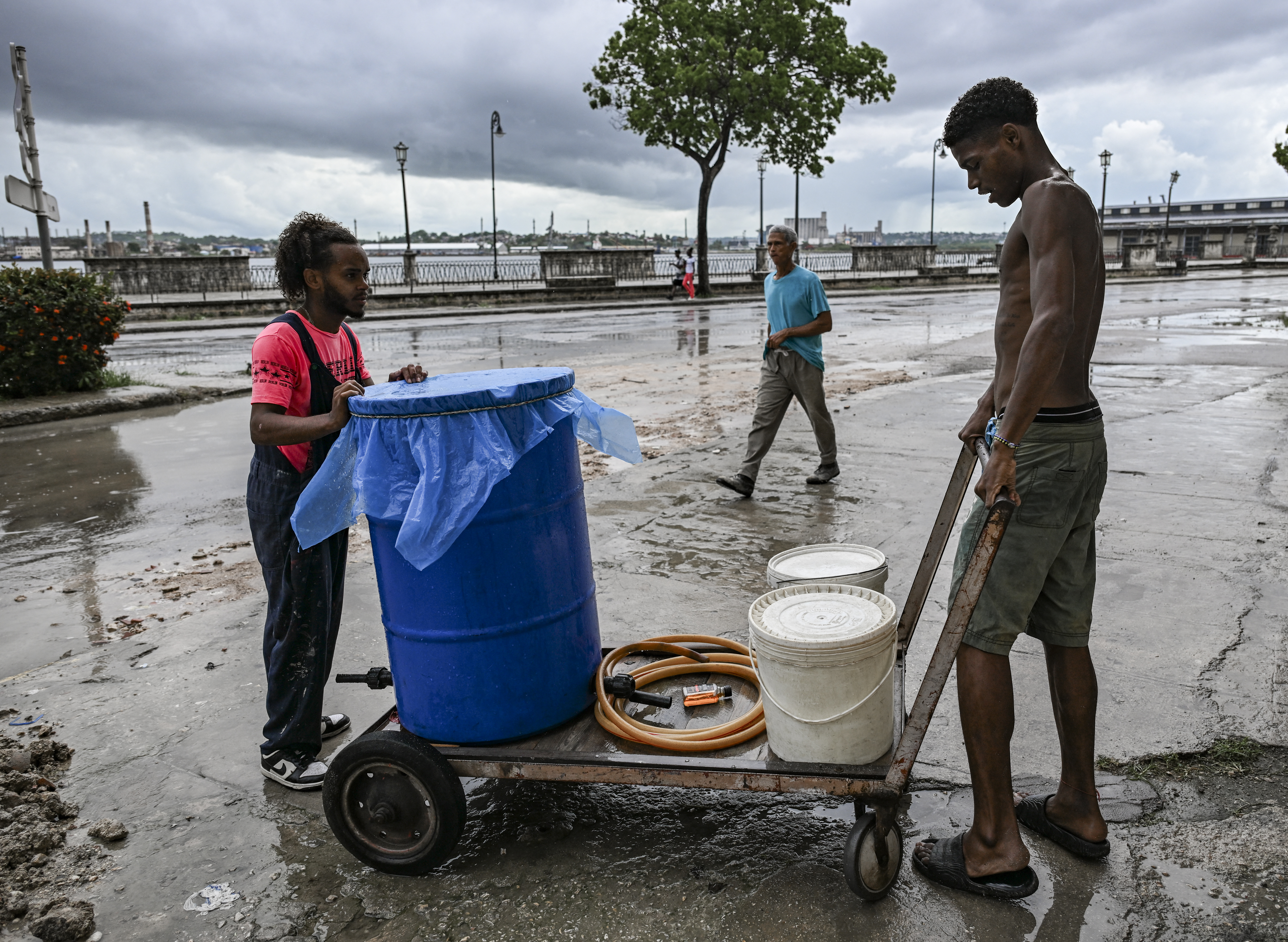 Young men load water containers onto a cart during a power outage in Havana on June 10, 2026. (Photo by YAMIL LAGE / AFP)