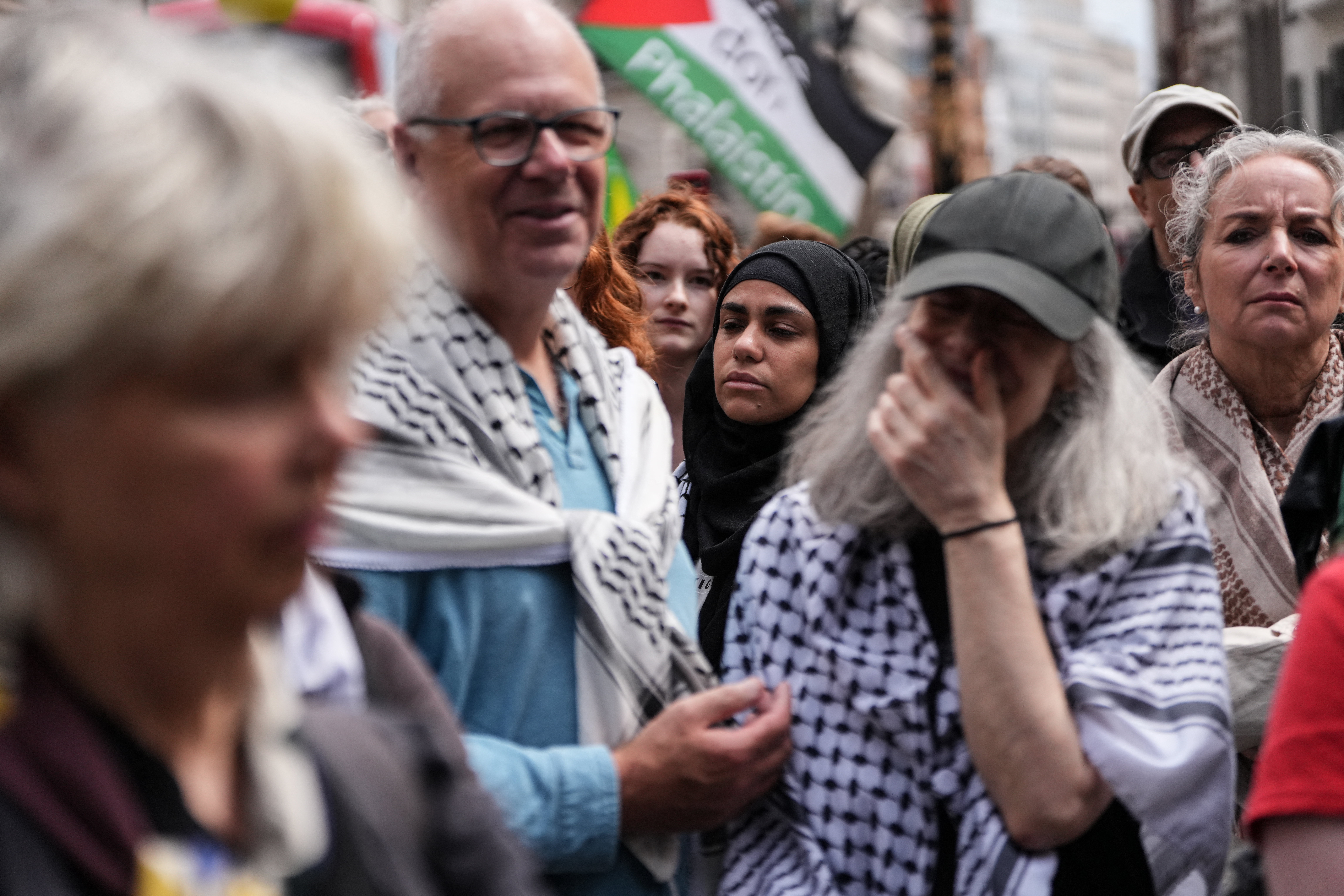 People stand listening to the court proceedings outside the Royal Courts Of Justice in central London on June 15, 2026, as the High Court rules on a legal standoff between the government and activist group Palestine Action.