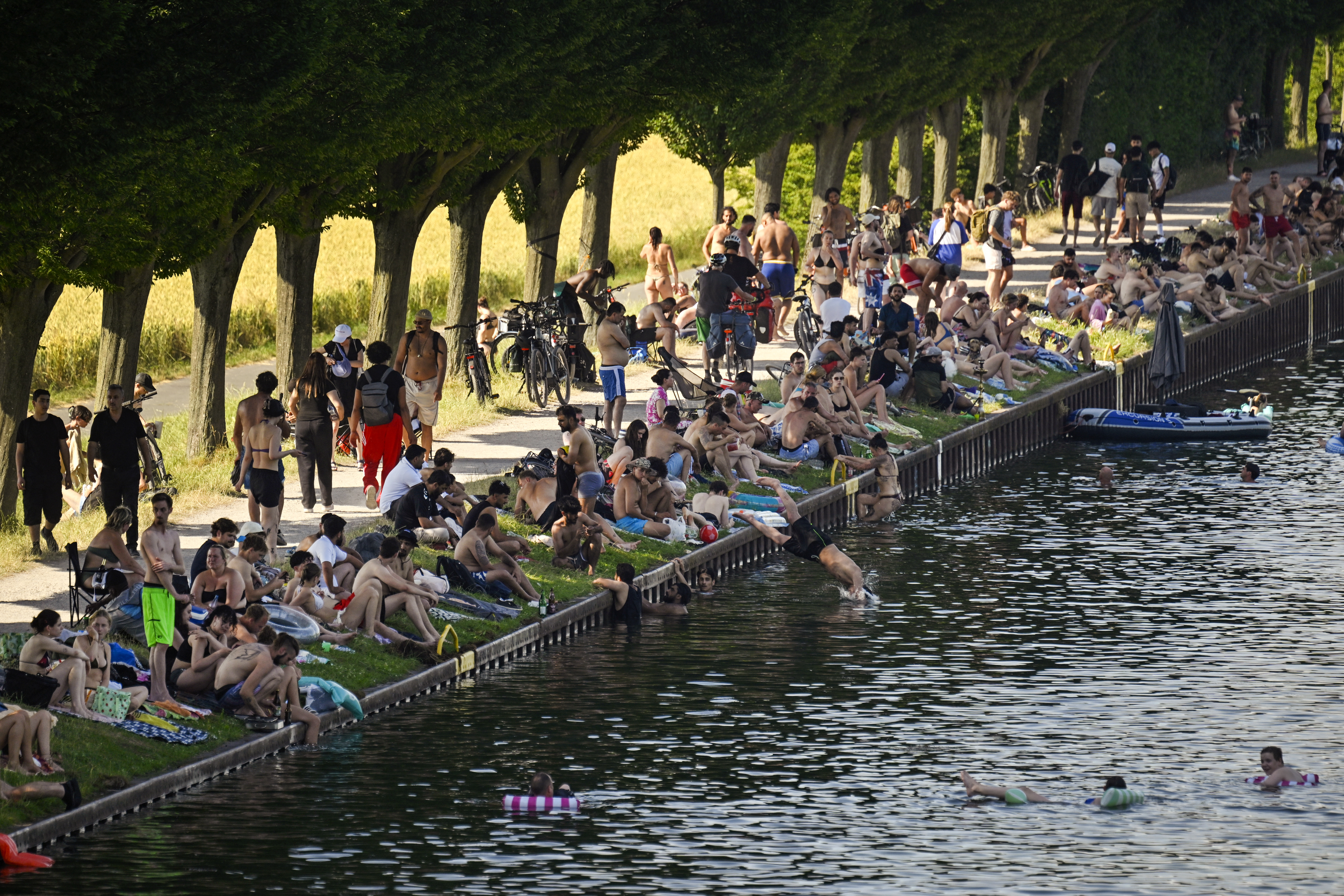 People sit at the side of the Dortmund-Ems Canal in Dortmund, western Germany on June 26, 2026 during a heatwave in Europe.
