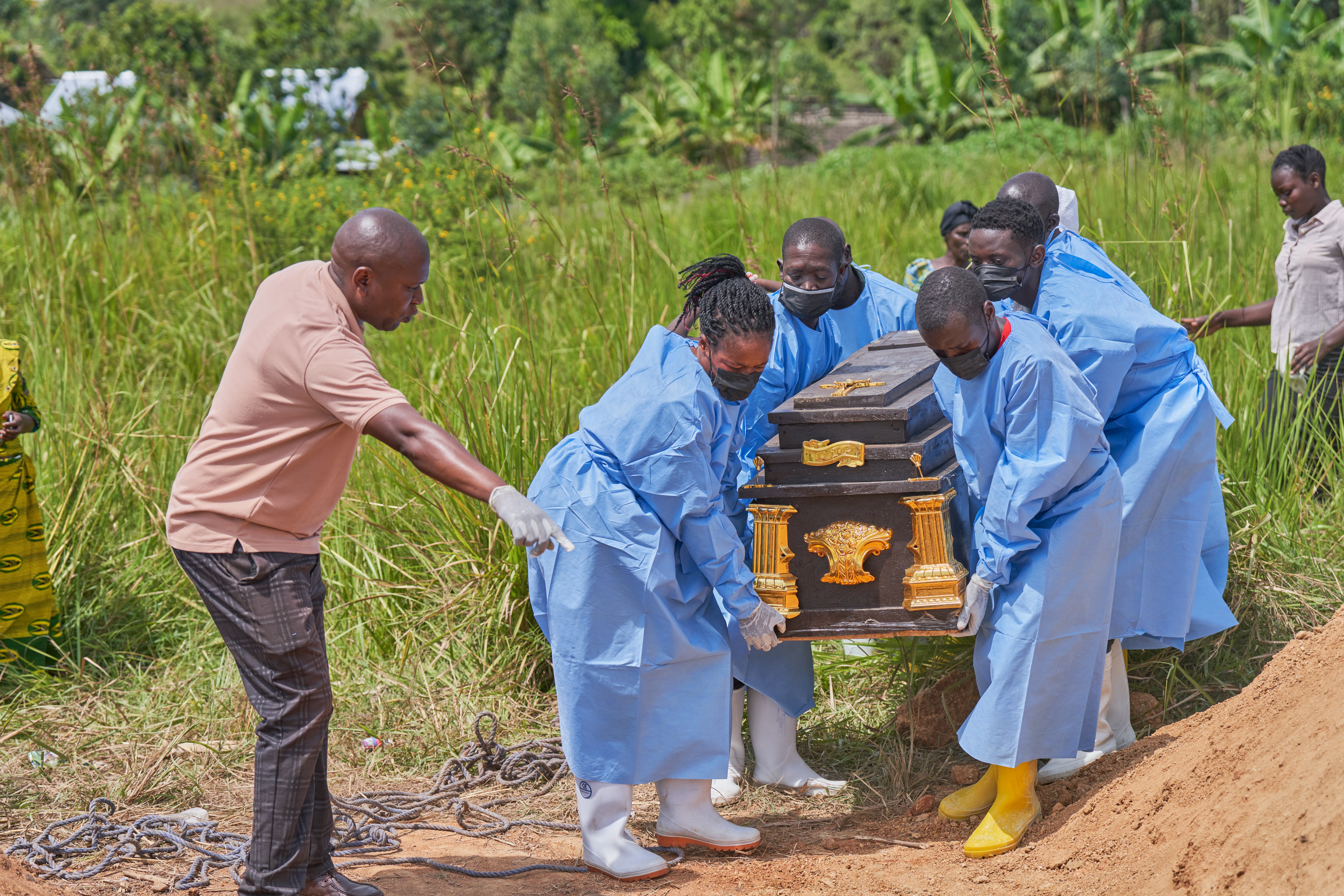 Medical personnel in protective suits carry a coffin.