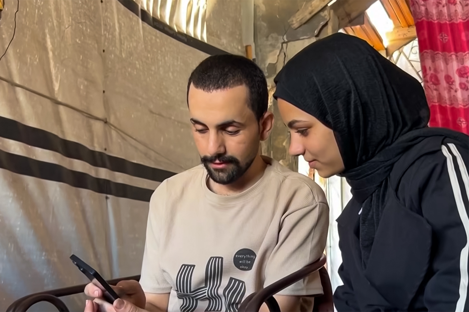 Hamada al-Banna sits with his fiancée inside a makeshift shelter in Gaza following his release from Israeli detention. His family had held a mourning wake for him after erroneously being informed he was killed.[Screengrab\Al Jazeera]