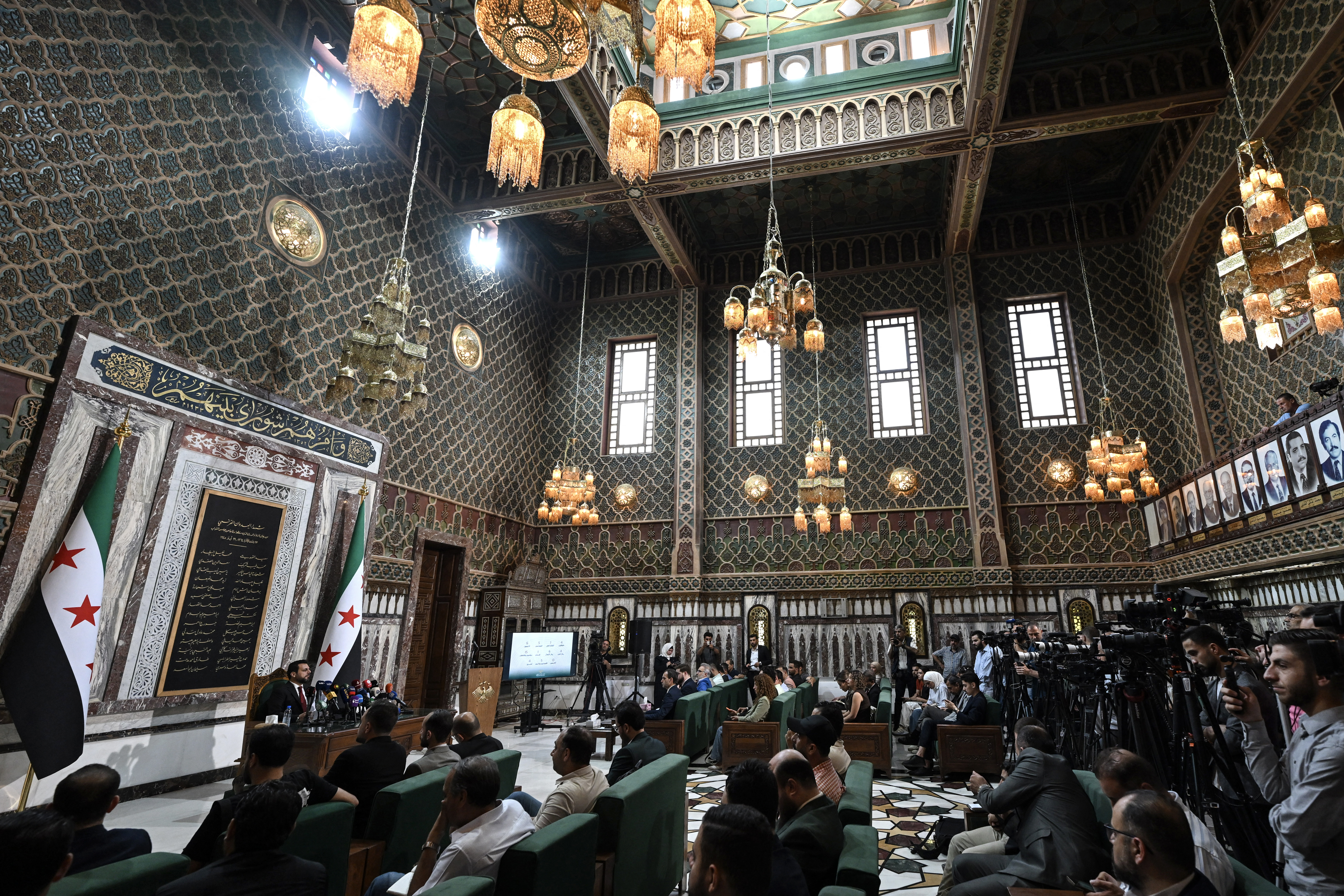 Mohammad Taha al-Ahmad (L), head of the higher electoral committee, speaks during a press conference announcing newly appointed lawmakers at the parliament in Damascus on July 1, 2026.