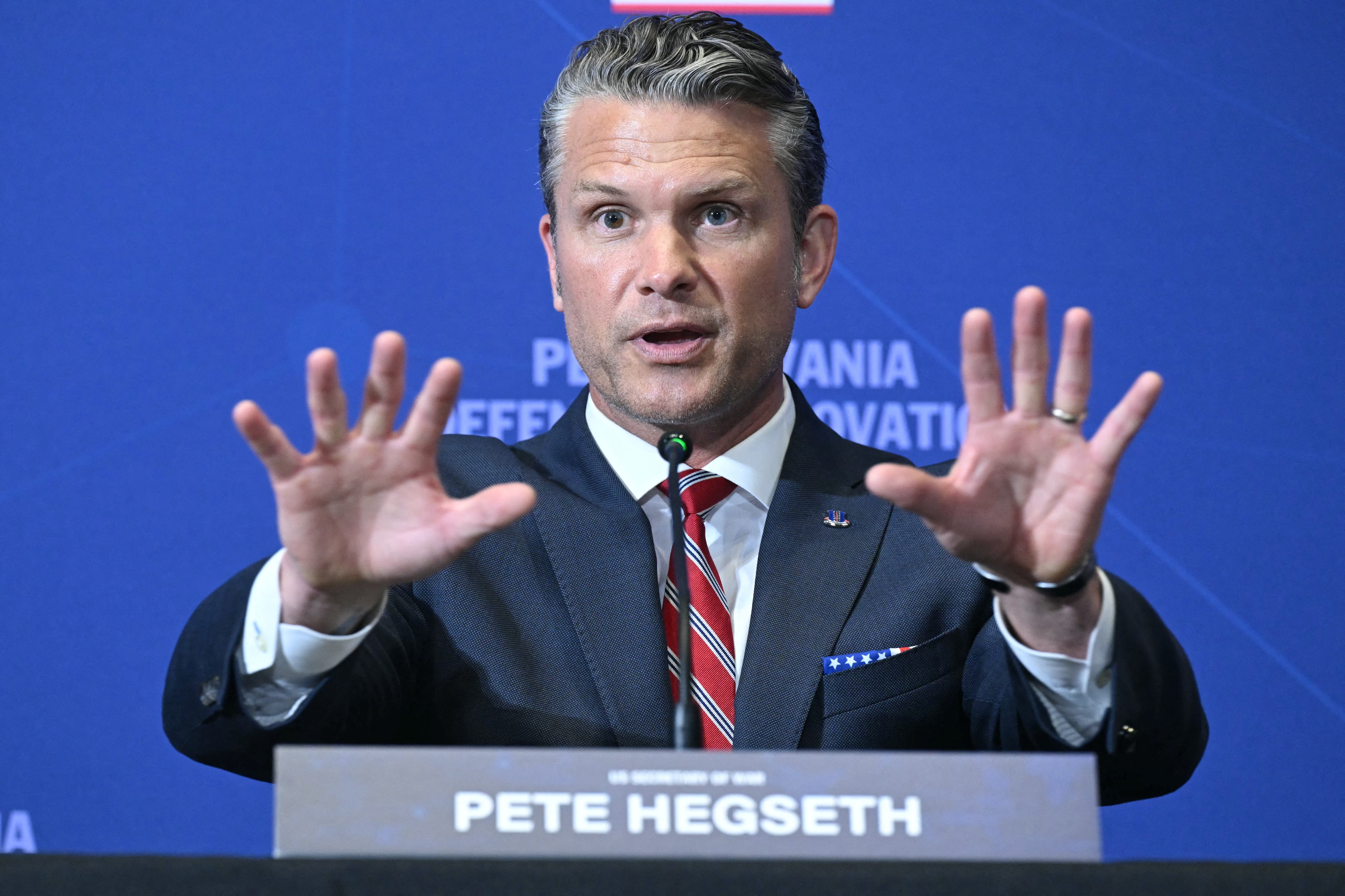 Pete Hegseth gestures while speaking at a podium during a defence summit