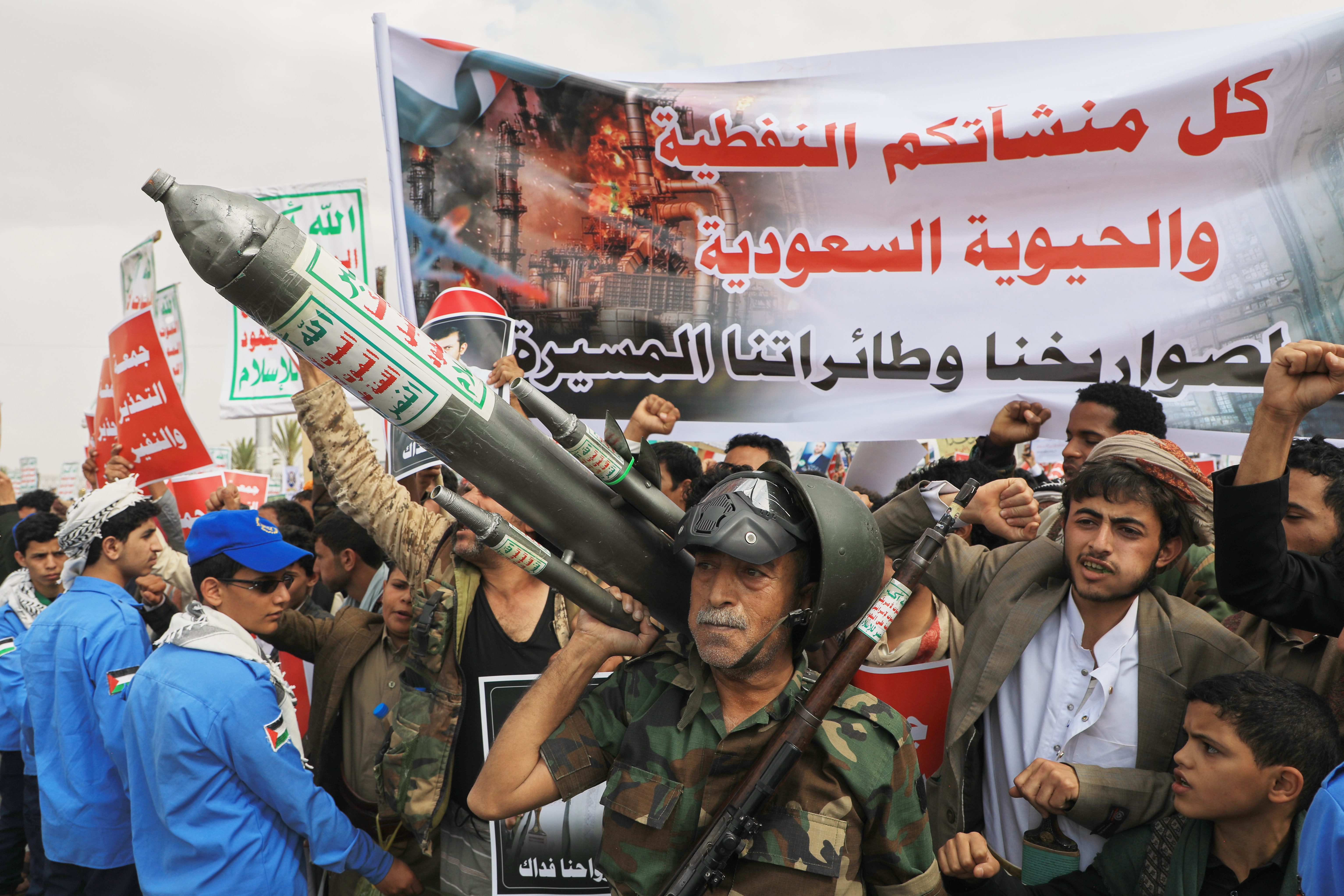 People hold a rally, brandishing banners and weapons.