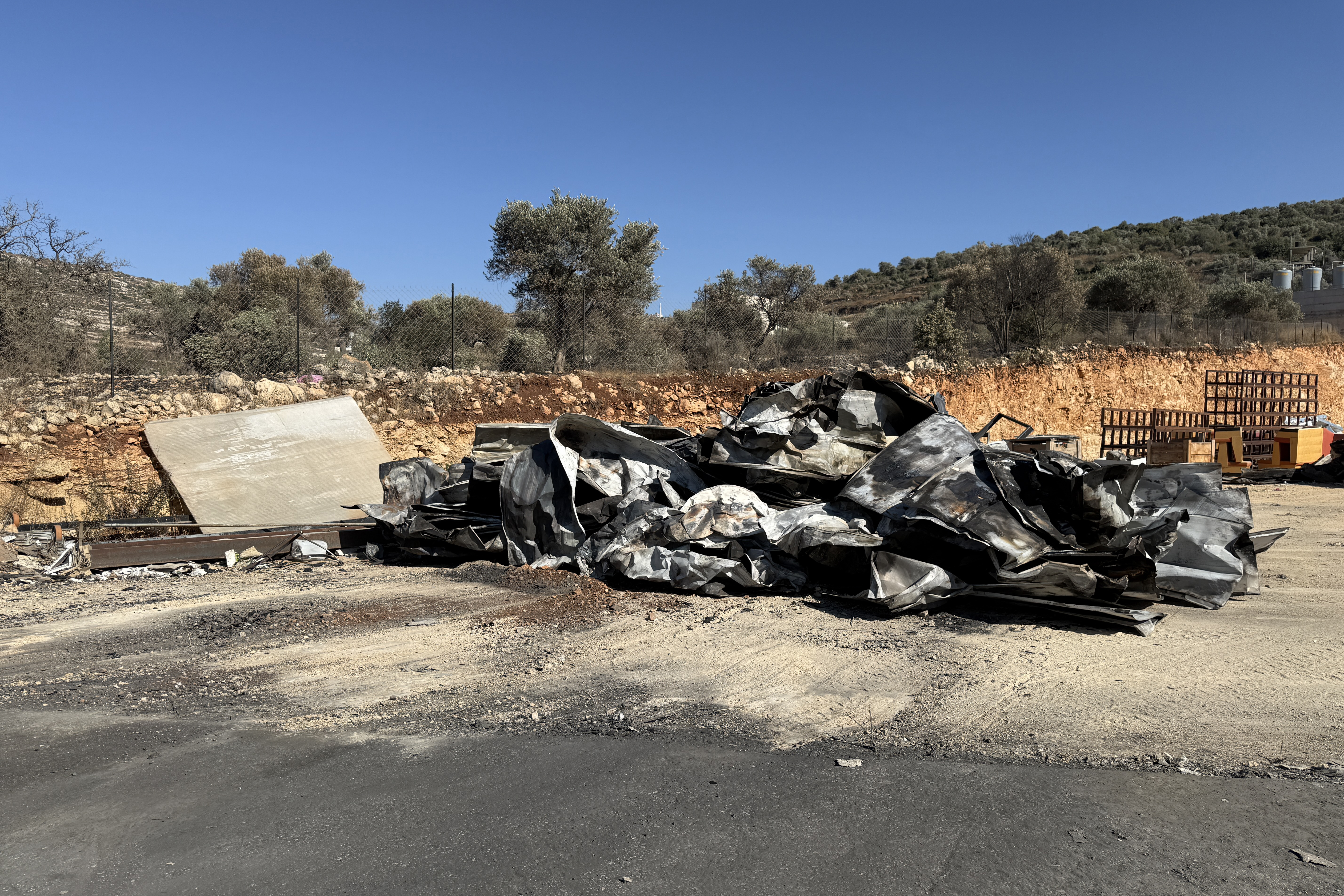 Burnt trees and scorched land are seen following an arson attack by Israeli settlers on the Al-Omari aluminum factory in Ein Sinia [Screengrab/Al Jazeera]
