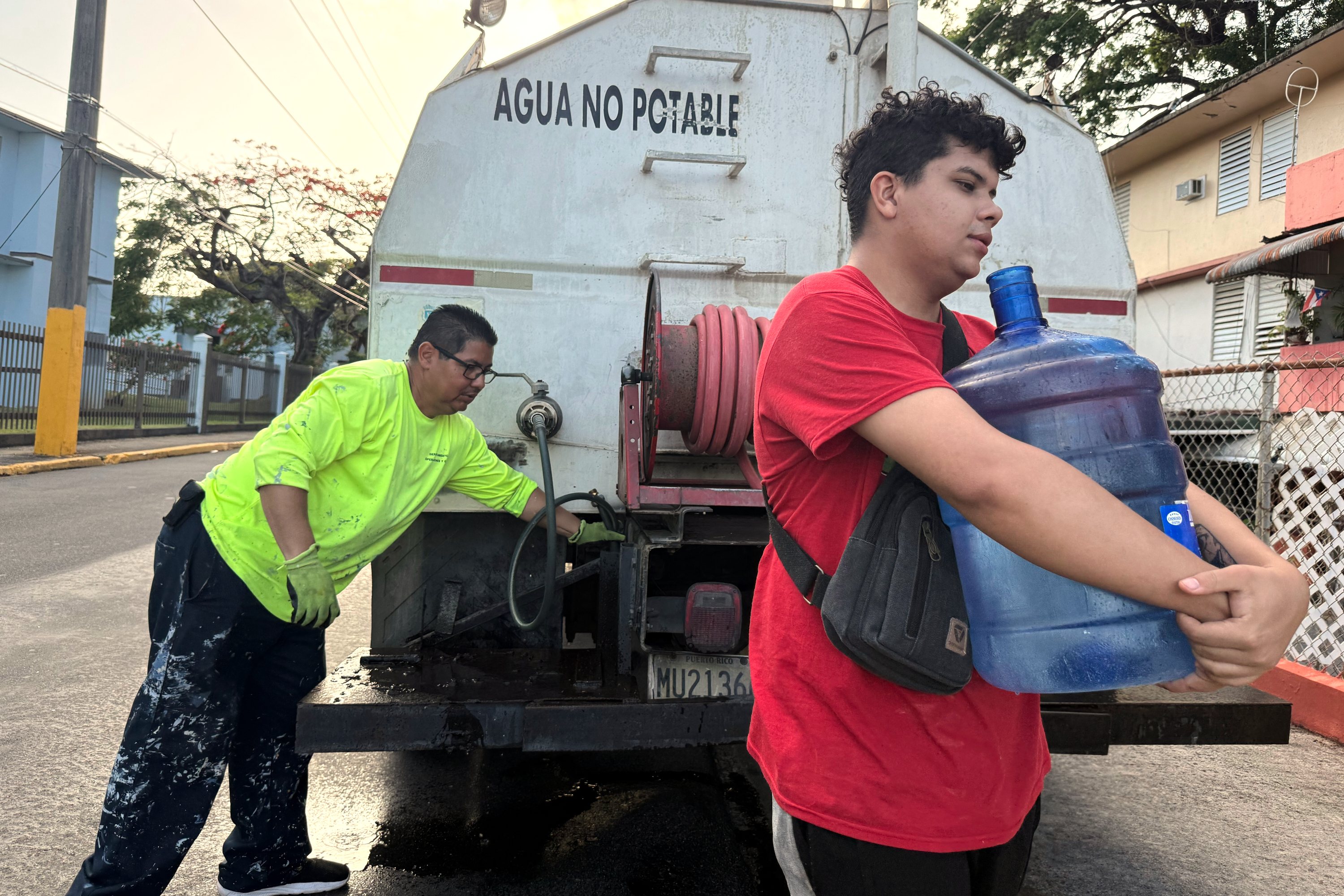 Bryan Pérez hauls a five-gallon water jug to his apartment in the Villa Kennedy public housing complex in San Juan, Puerto Rico, June 10, 2026