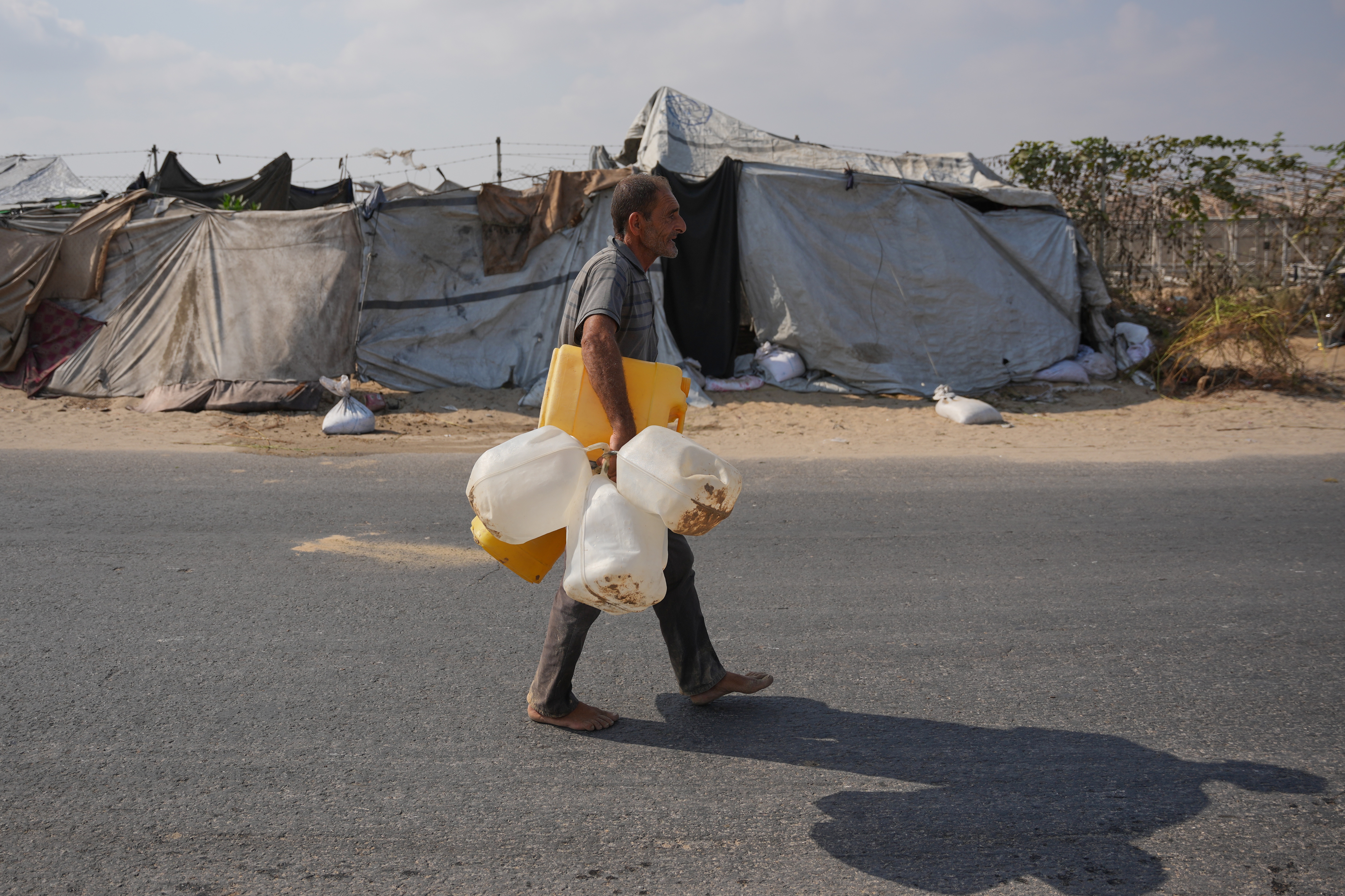 man carries several containers to seek water