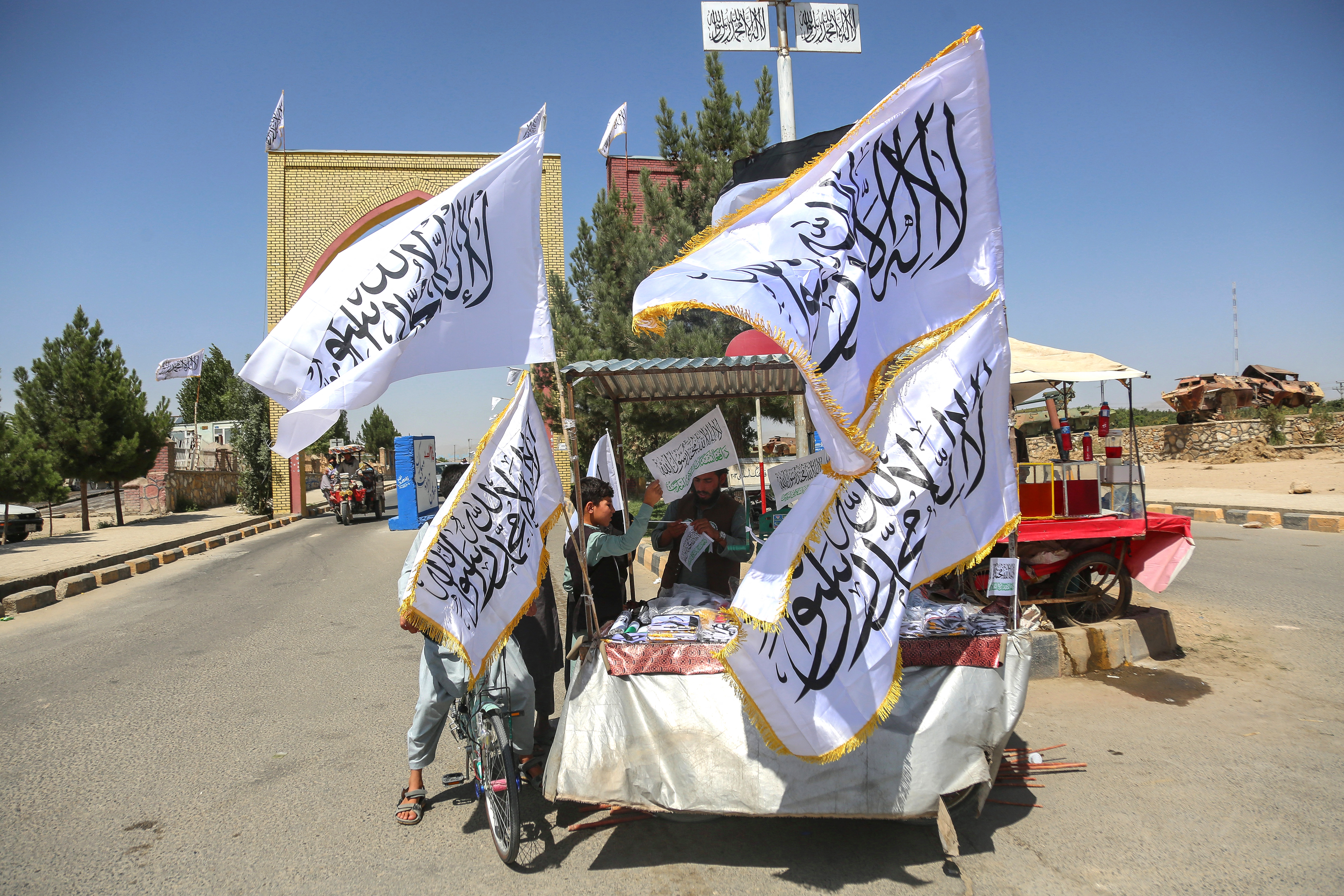 An Afghan boy buys a Taliban flag from a roadside vendor in Afghanistan's Ghazni province on August 14, 2026 ahead of the fifth anniversary of the Taliban government's return to power. [Mohammad Faisal Naweed/AFP]