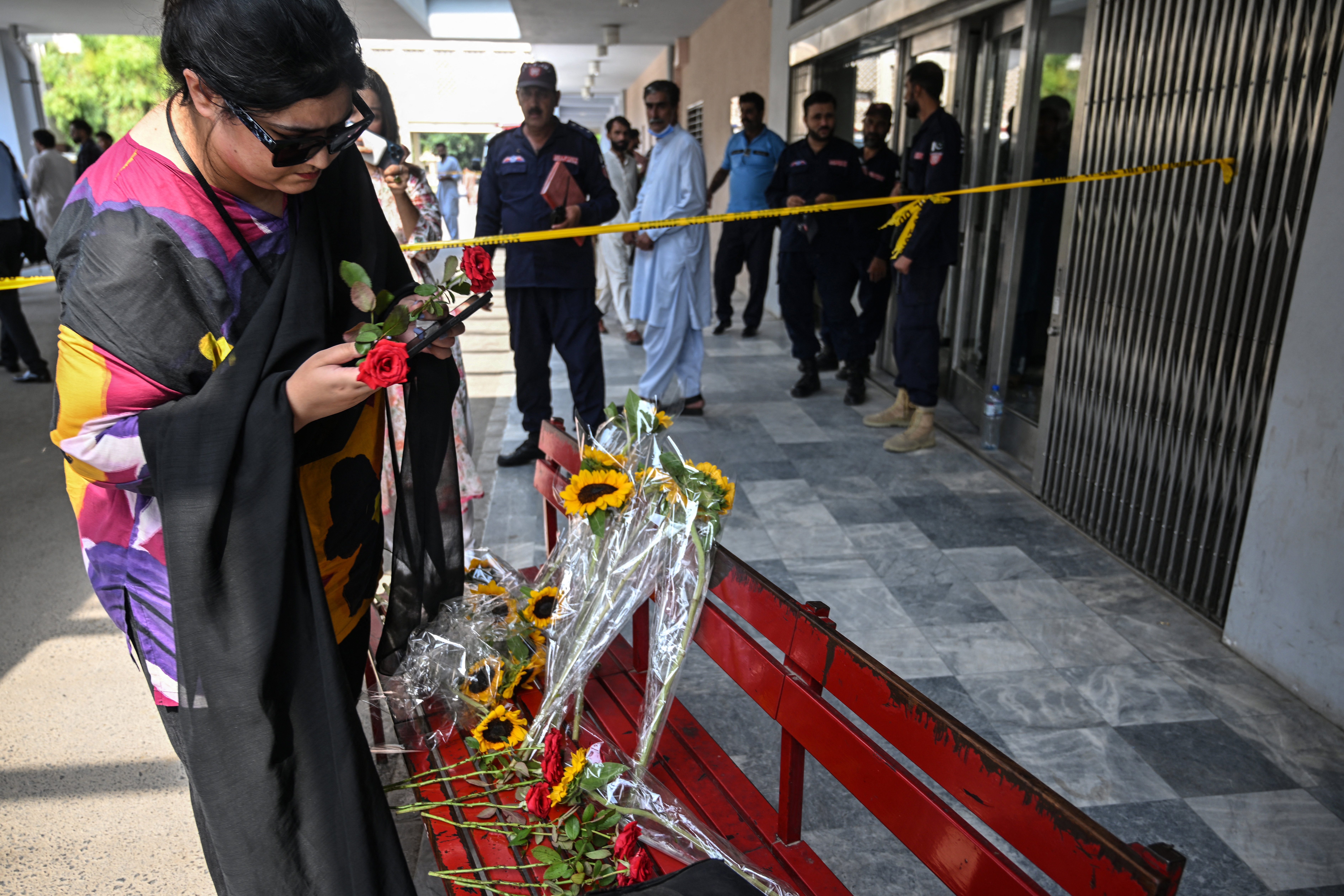 A woman places a flower outside the Mother and Child Health ward as she pays homage to infants killed in a fire at the Pakistan Institute of Medical Sciences (PIMS) Hospital in Islamabad on August 27, 2026.