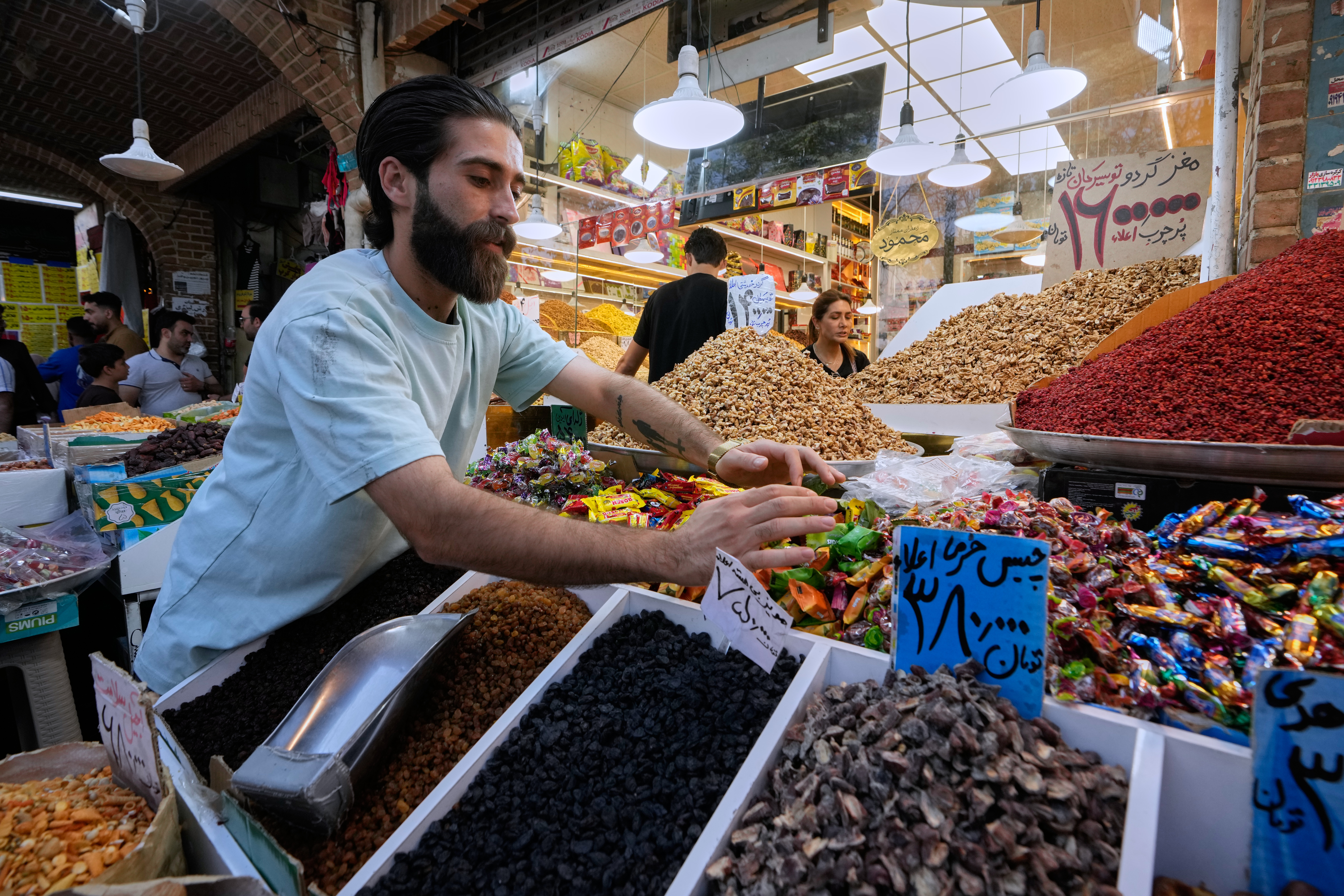 A shopkeeper arranges items at his shop at Tehran's Grand Bazaar in Tehran, Iran, Tuesday, Aug. 25, 2026. (AP Photo/Vahid Salemi)