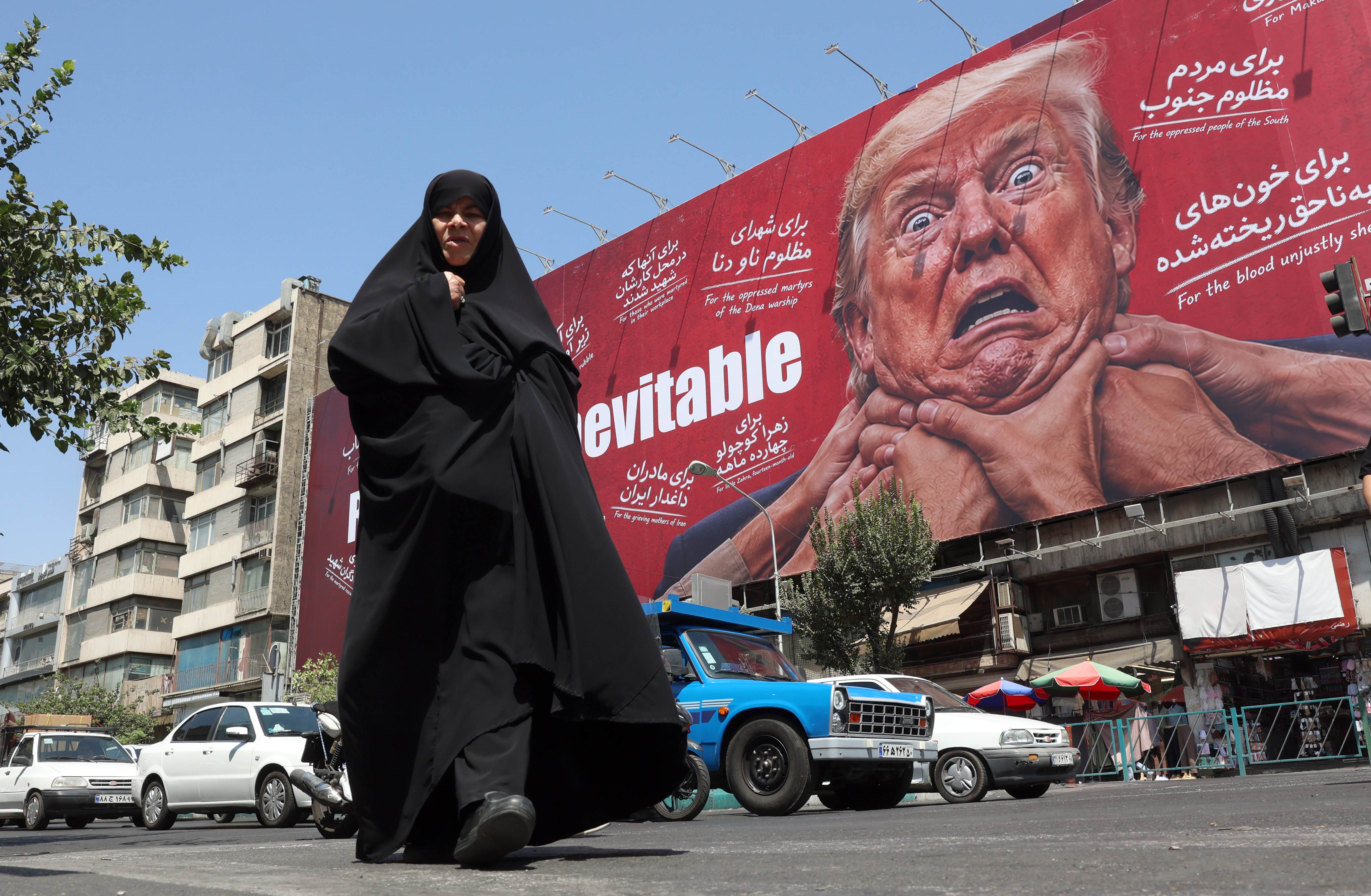 A woman walks next to an anti-Trump billboard.