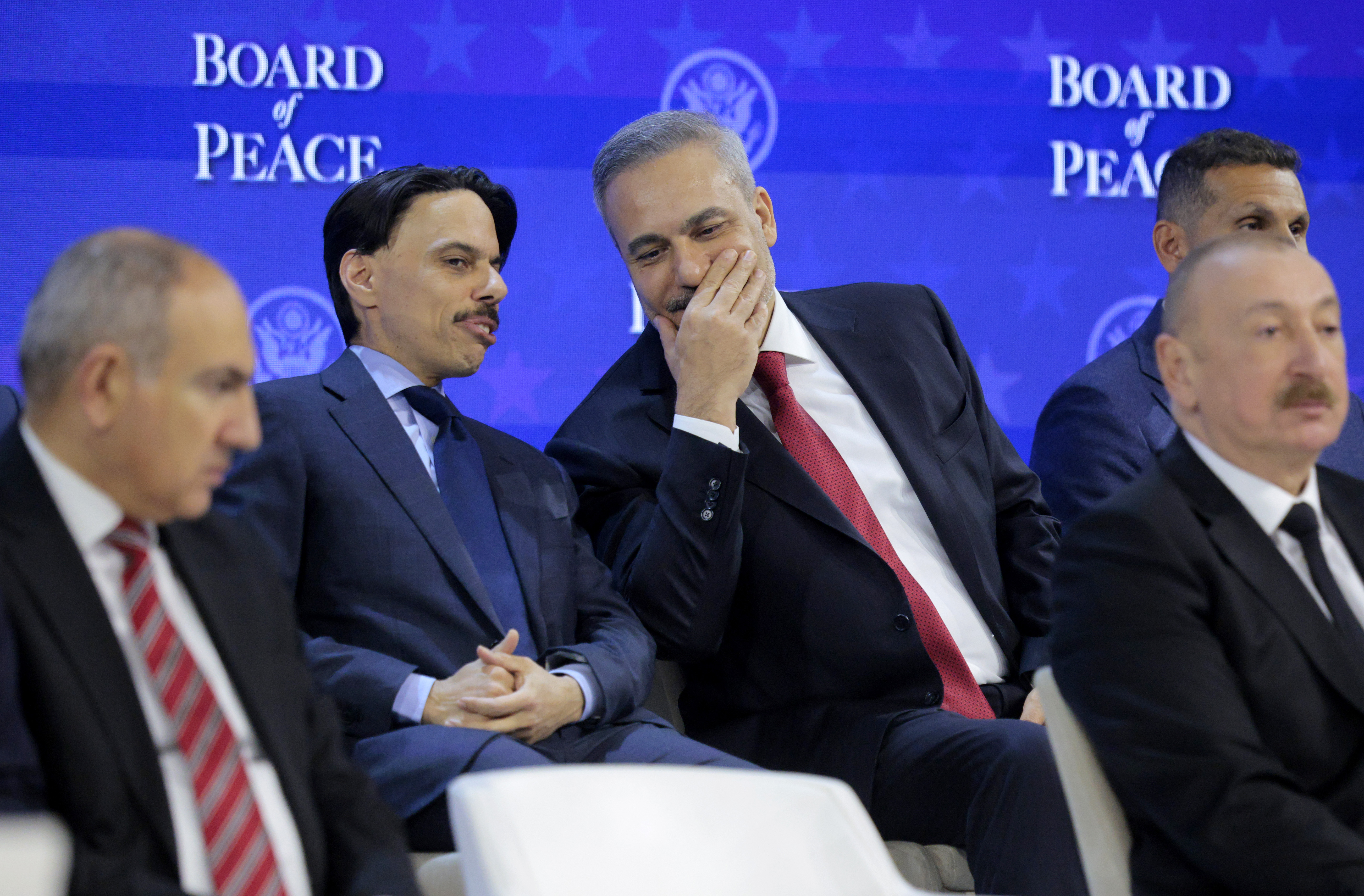 DAVOS, SWITZERLAND - JANUARY 22: Saudi Arabia's Foreign Minister Faisal bin Farhan (L) speaks with Turkey's Foreign Minister Hakan Fidan as U.S. President Donald Trump presents the “Board of Peace” at the World Economic Forum (WEF) on January 22, 2026 in Davos, Switzerland. The US-backed “Board of Peace” is intended to administer the fragile ceasefire in the Gaza Strip after the war between Israel and Hamas. The final makeup of the board has not been confirmed. (Photo by Chip Somodevilla/Getty Images)