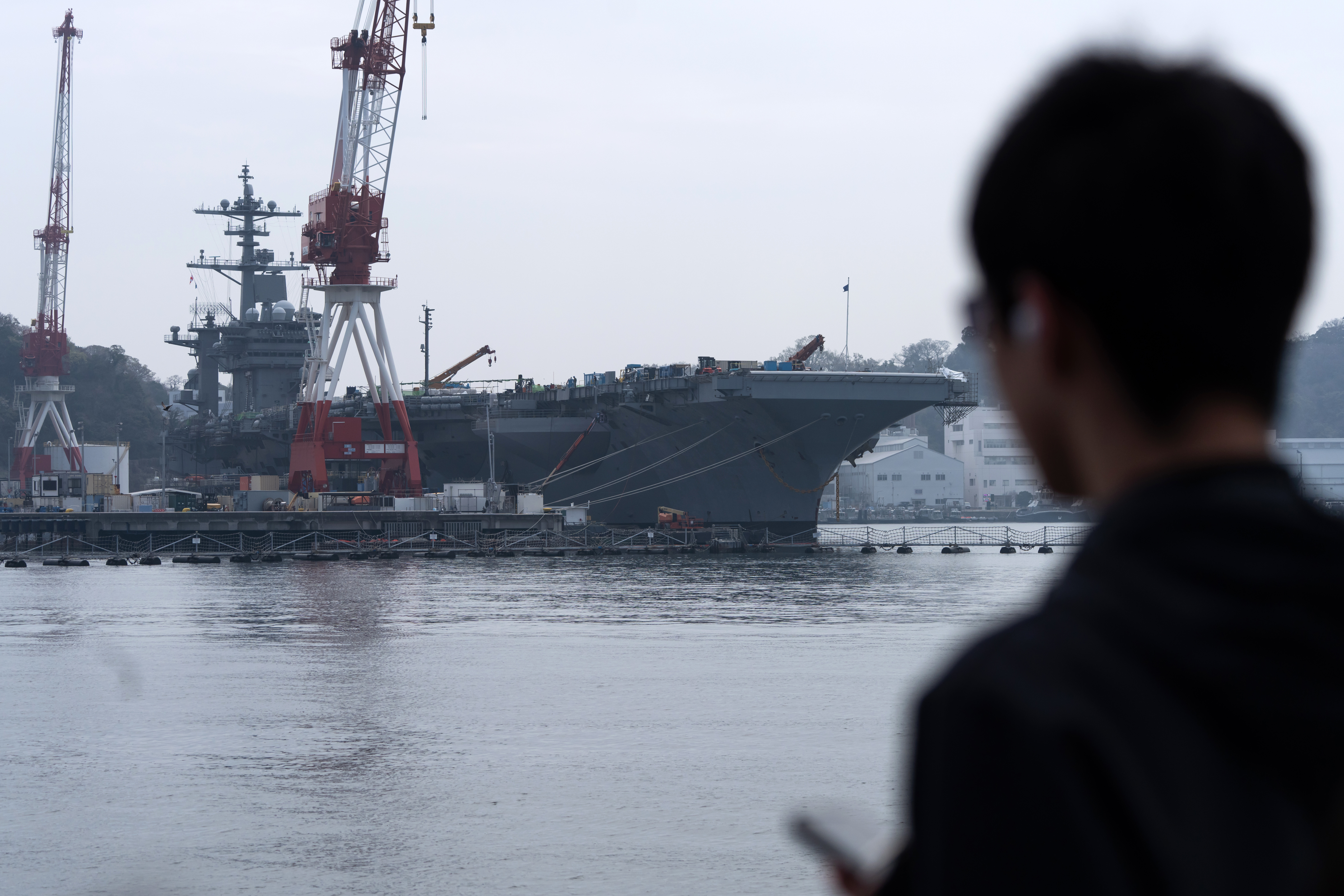 YOKOSUKA, JAPAN - MARCH 30: A passenger on a tour boat looks at the USS George Washington aircraft carrier docked at U.S. Fleet Activities Yokosuka on March 30, 2026 in Yokosuka, Japan. (Photo by Tomohiro Ohsumi/Getty Images)