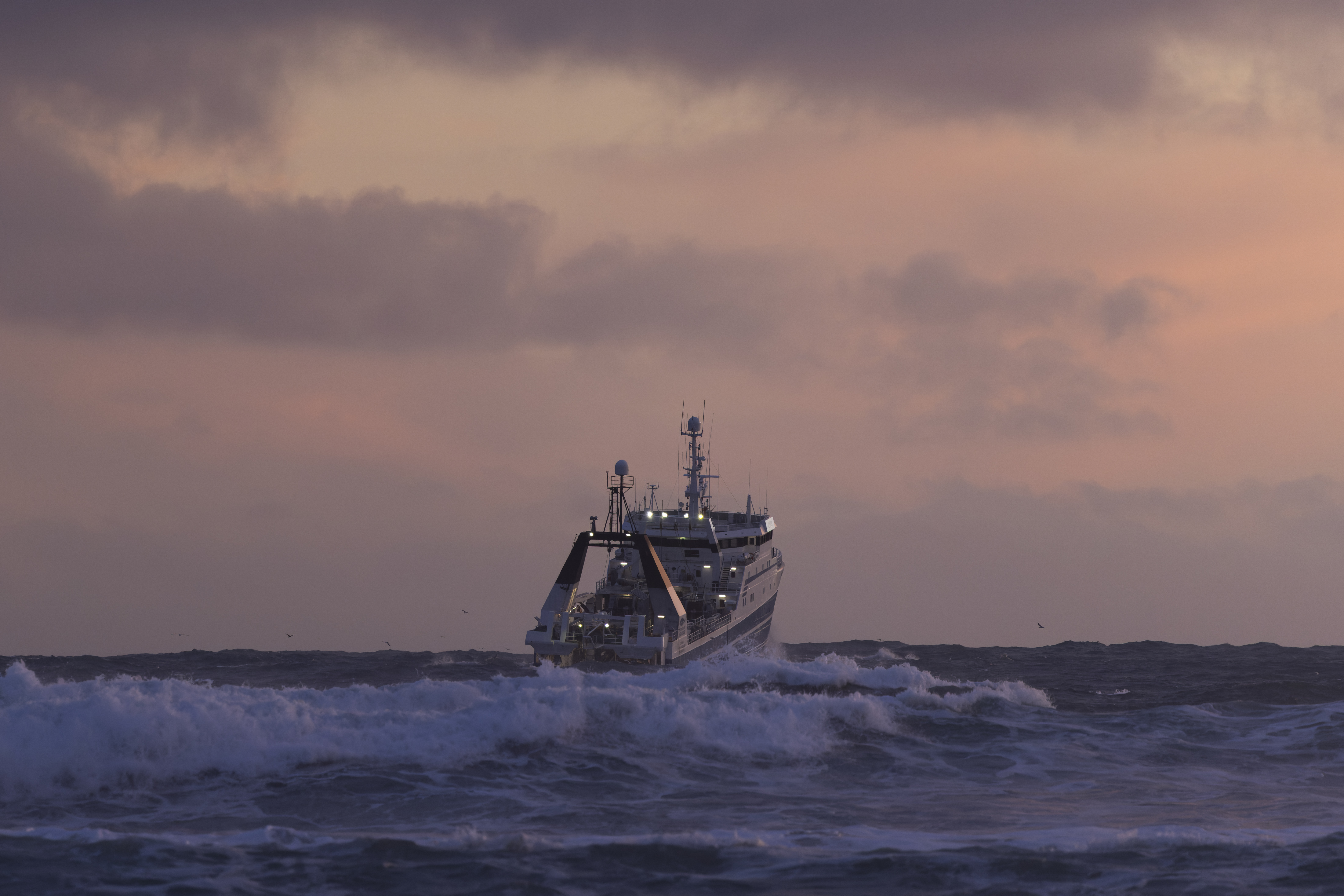 GRINDAVIK, ICELAND - DECEMBER 20: A fishing boat battles rough seas on December 20, 2025 in Grindavik, Iceland. The town of Grindavík, about 50km southwest of the capital, Reykjavík, was home to roughly 3,700 people before repeated volcanic eruptions along the Sundhnúkur crater row first forced evacuations in November 2023. In January 2024, lava intrusions destroyed several houses after a fissure opened inside defensive berms, while a tectonic fissure cuts through the town. One worker was killed after falling into the fissure during repairs. The Svartsengi power plant and Blue Lagoon lie just north, directly above accumulating magma, with both facilities crucial for Iceland's economy and tourism. The most recent eruption ended in August 2025, but the Icelandic Meteorological Office warns that "life-threatening conditions remain" and "an eruption is considered likely." The fishing community has since partially reopened, with limited services. Despite warnings, some residents have returned, as debate continues over the town's future. (Photo by Brook Mitchell/Getty Images)