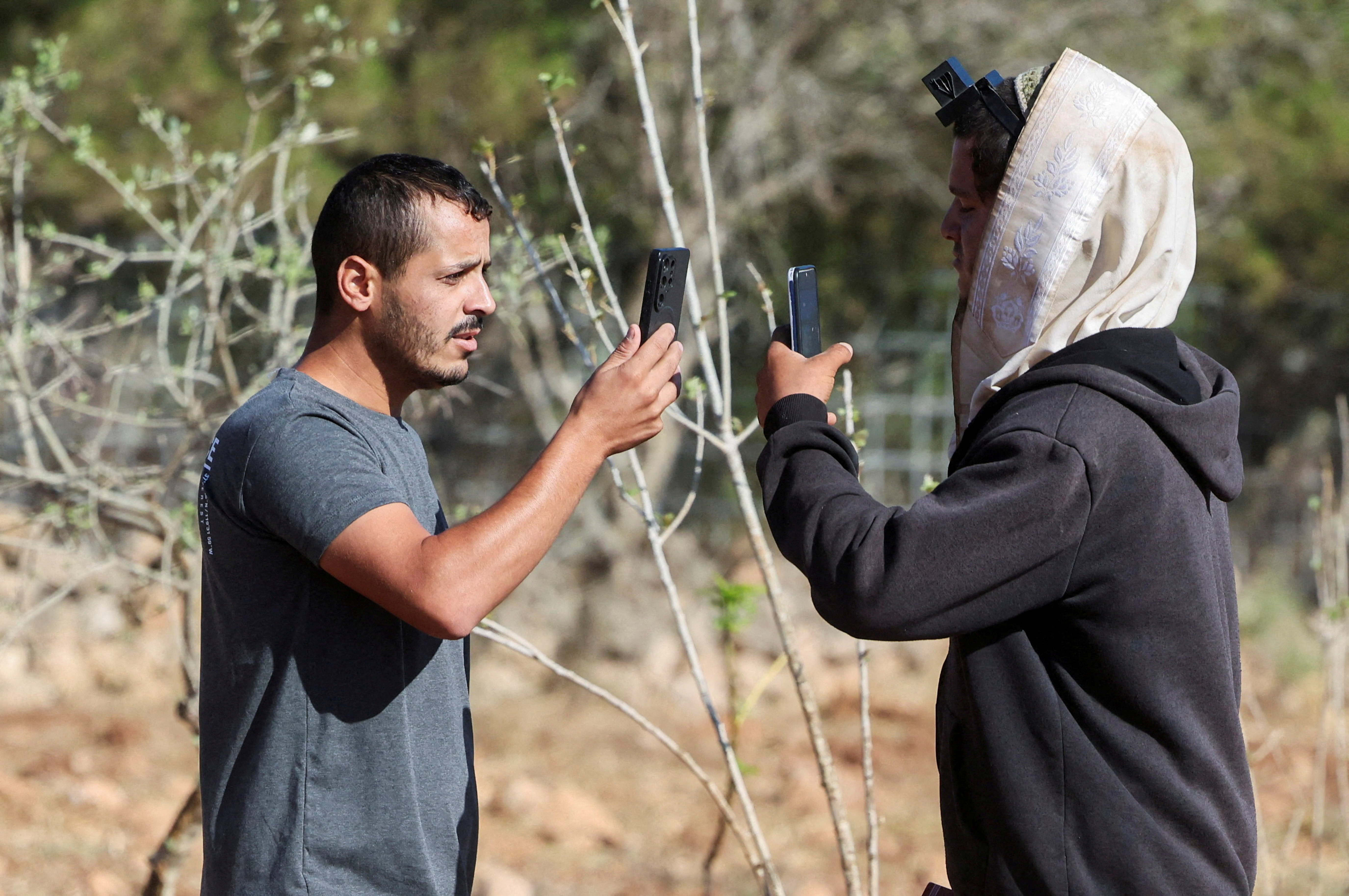 FILE PHOTO: Yousef Hassan (L), whose house was encircled by militant settlers and later taken over by the military, films an Israeli settler (R) who entered the property of Palestinian-American Loui Ridi, in Qusra, Israeli-occupied West Bank, August 18, 2026. REUTERS/Ammar Awad/File Photo