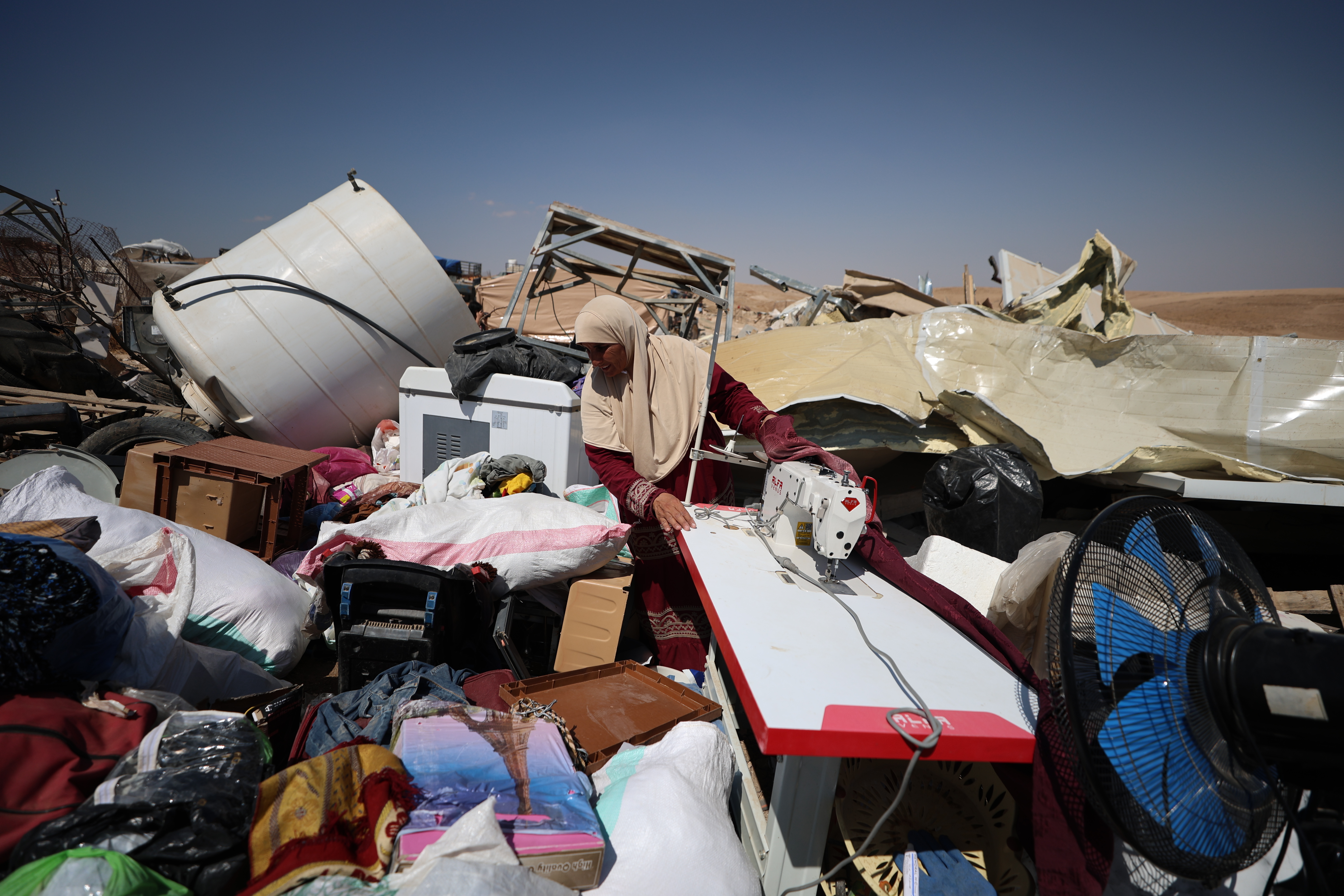 Woman looks through rubble and destroyed items