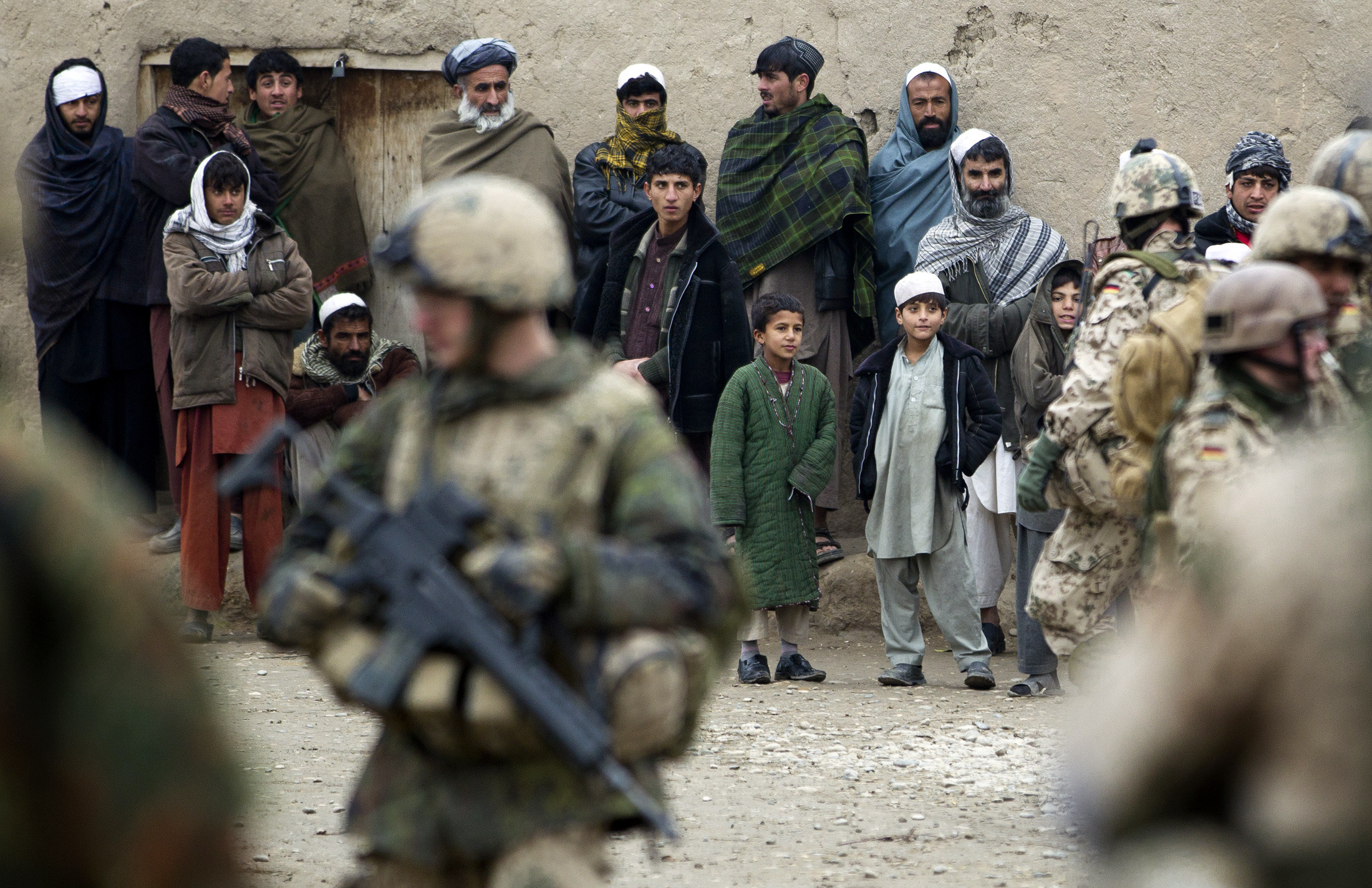 Locals look at German soldiers of the International Security Assistance Force (ISAF) approaching them during a patrol in the village of Isa Khel in Chahar Dara district December 16, 2011. [Thomas Peter/Reuters]