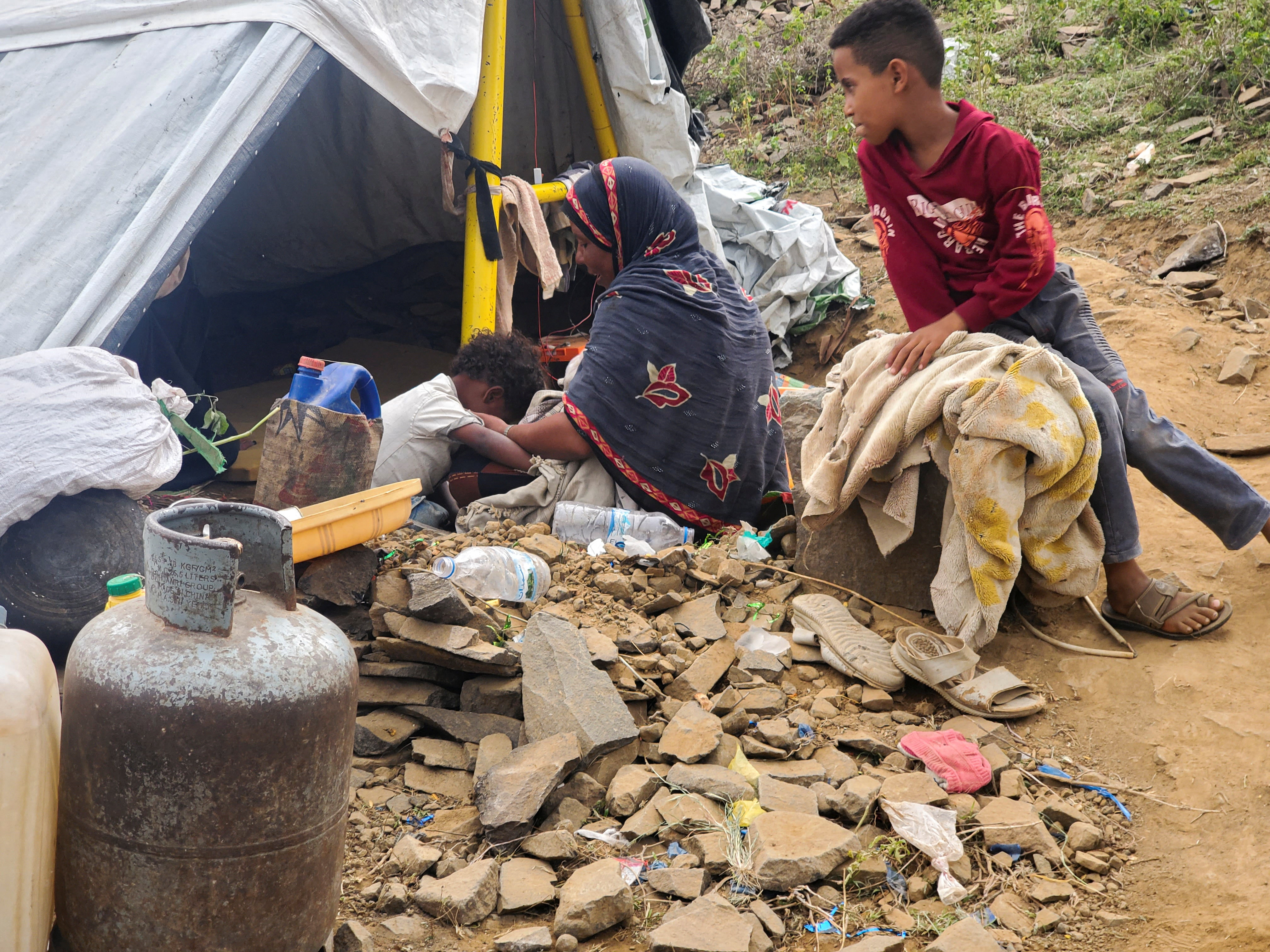 A woman sits with her children outside a tent at a makeshift camp for people displaced by clashes between Iran-aligned Houthi fighters and Saudi-backed Yemeni government forces, in Taiz province, Yemen, September 14, 2026. Picture taken with a mobile phone. REUTERS/Stringer