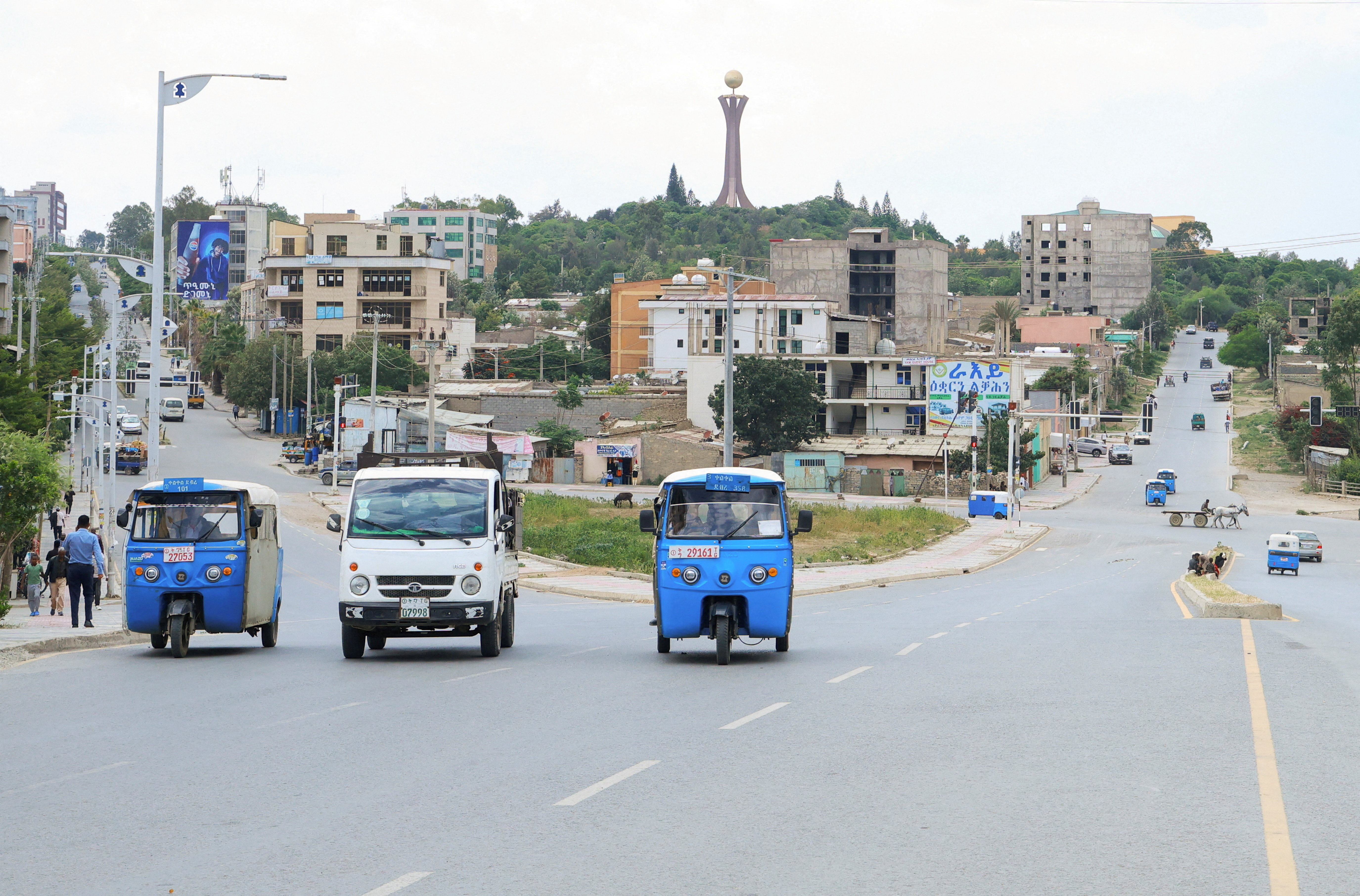 Rickshaw taxis and motorists are seen in a street.