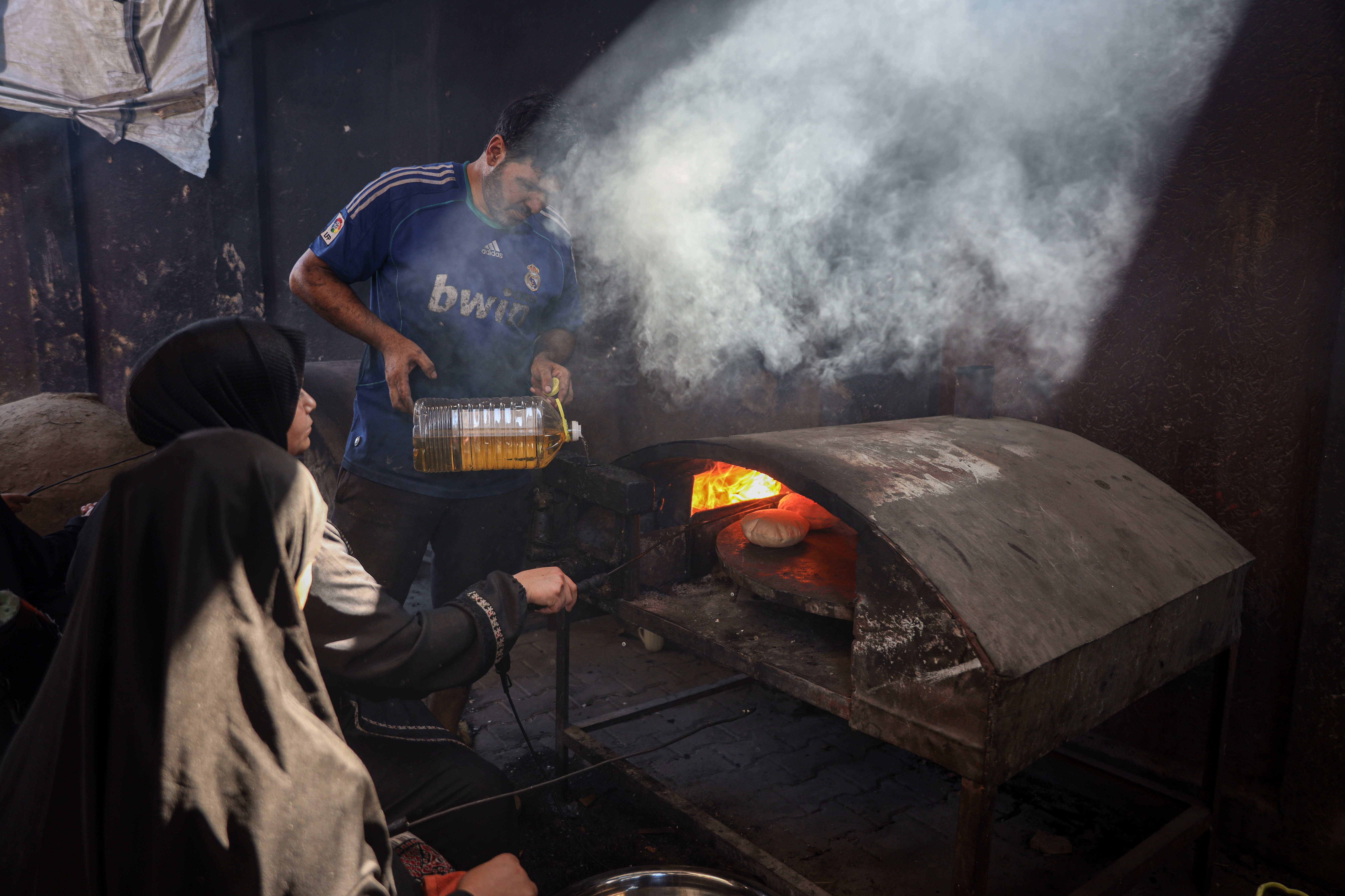 The communal oven burns firewood, sometimes mixed with used cooking oil to help strengthen the flames and keep the oven hot