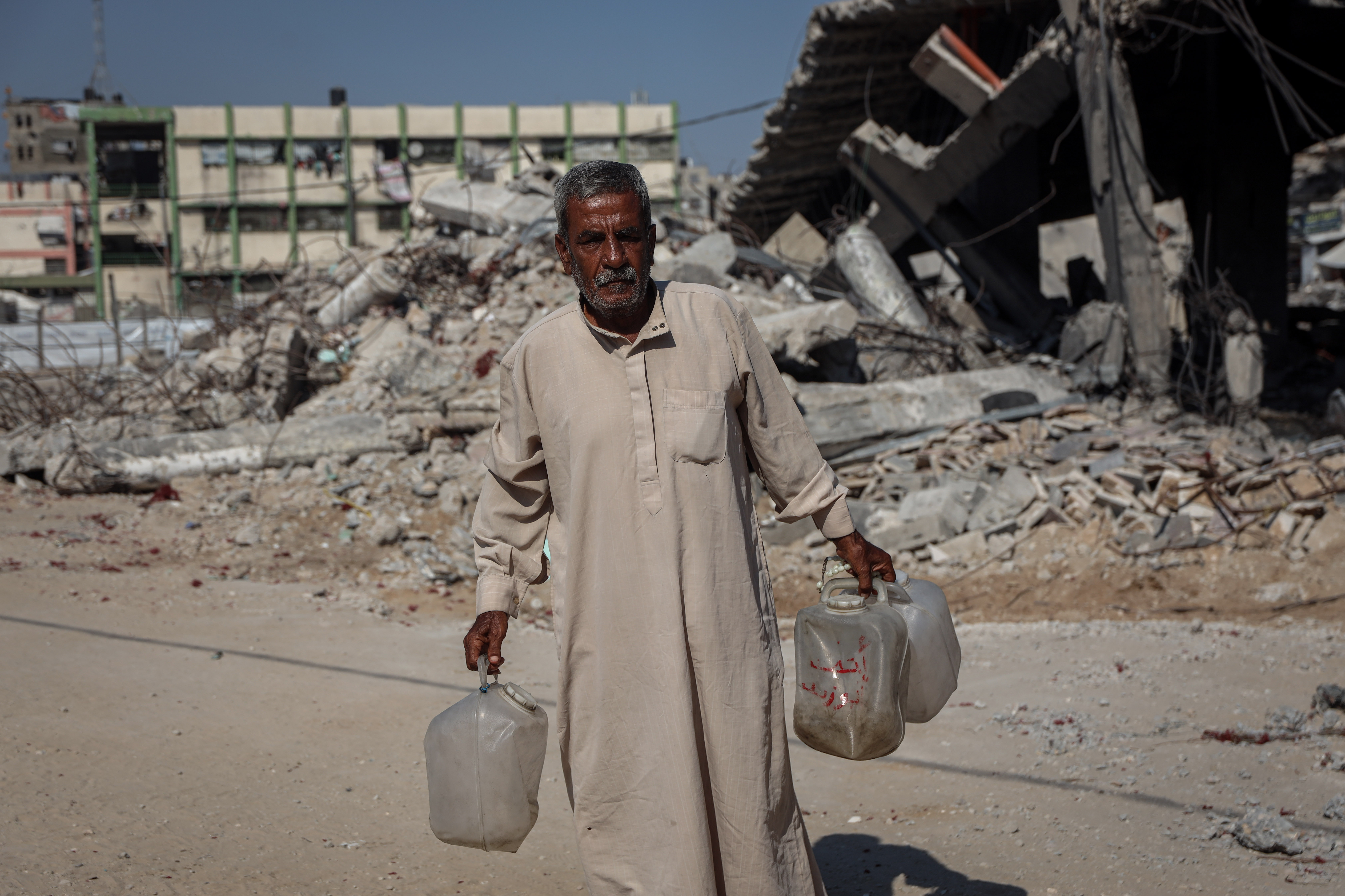 Elderly man holds empty water cans