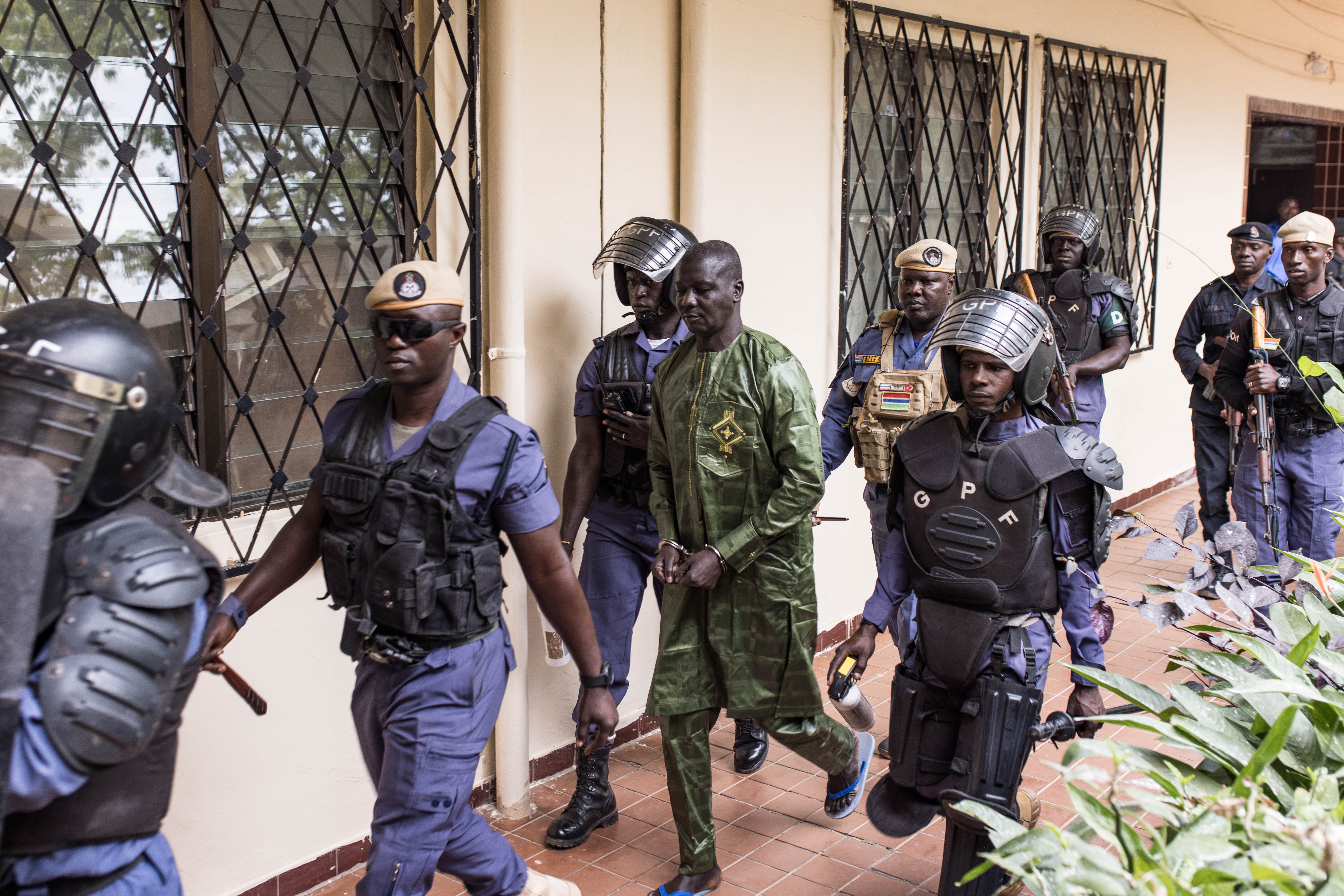 Security escourt Sanna Manjang (C), a former member of a Gambian death squad suspected of shooting AFP's correspondent Deyda Hydara in 2004, as he arrives at court ahead of his hearing at the High Court in Banjul on January 15, 2025. [Muhamadou Bittaye/AFP]