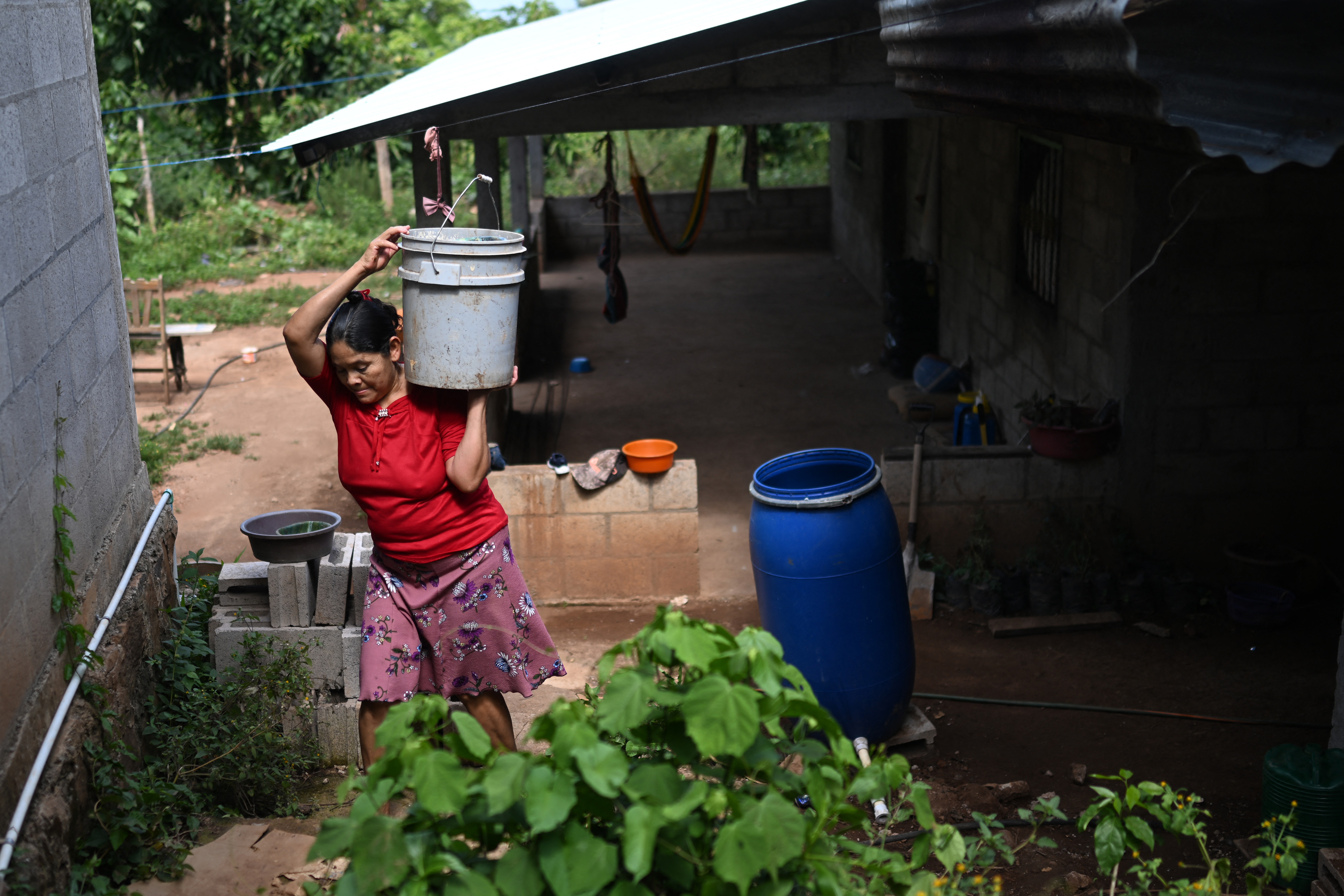 A Salvadoran woman carries water to irrigate crops.