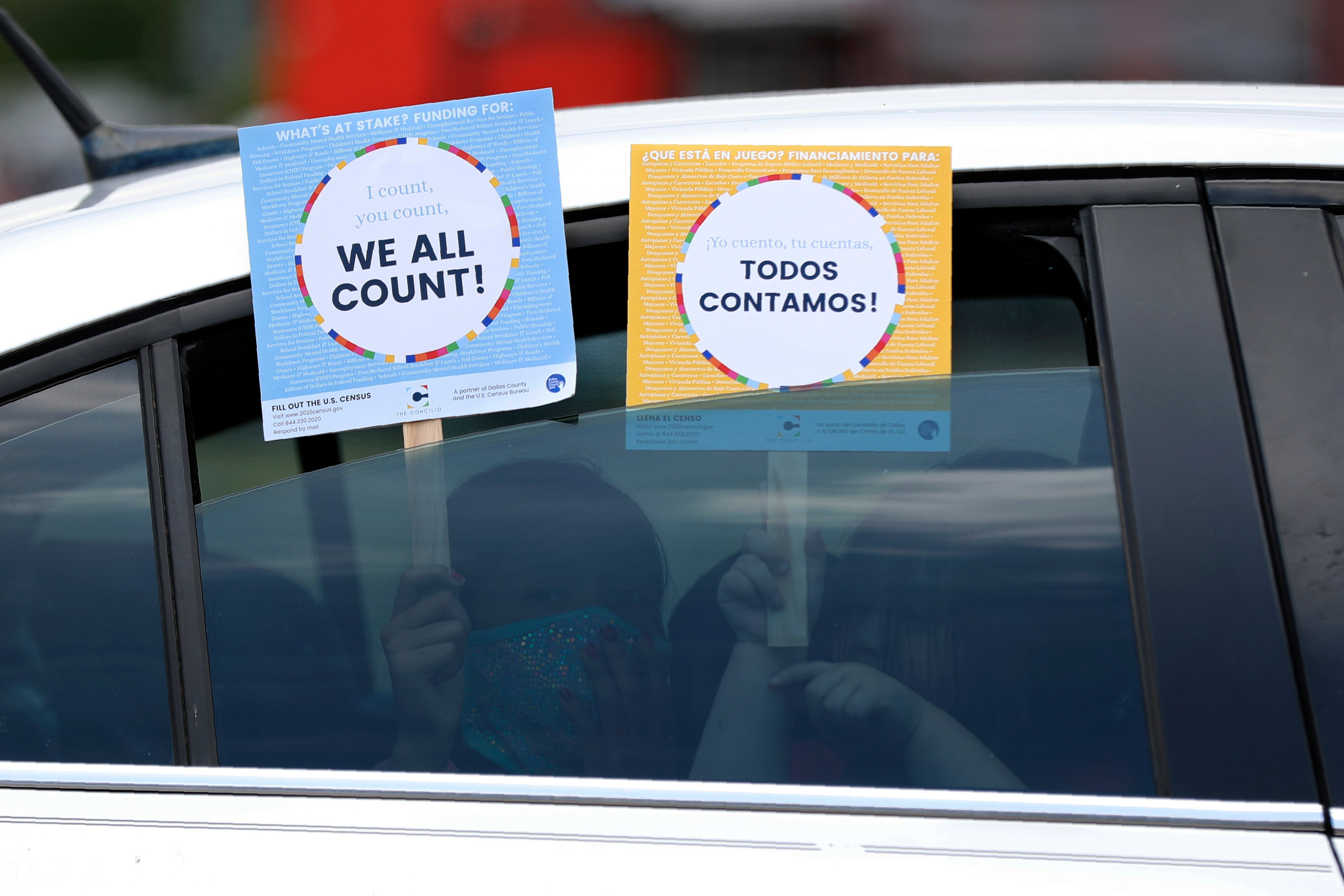 FILE - Two young children hold signs through the car window that make reference to the 2020 U.S. Census as they wait in the car with their family at an outreach event in Dallas, June 25, 2020. (AP Photo/Tony Gutierrez, File)