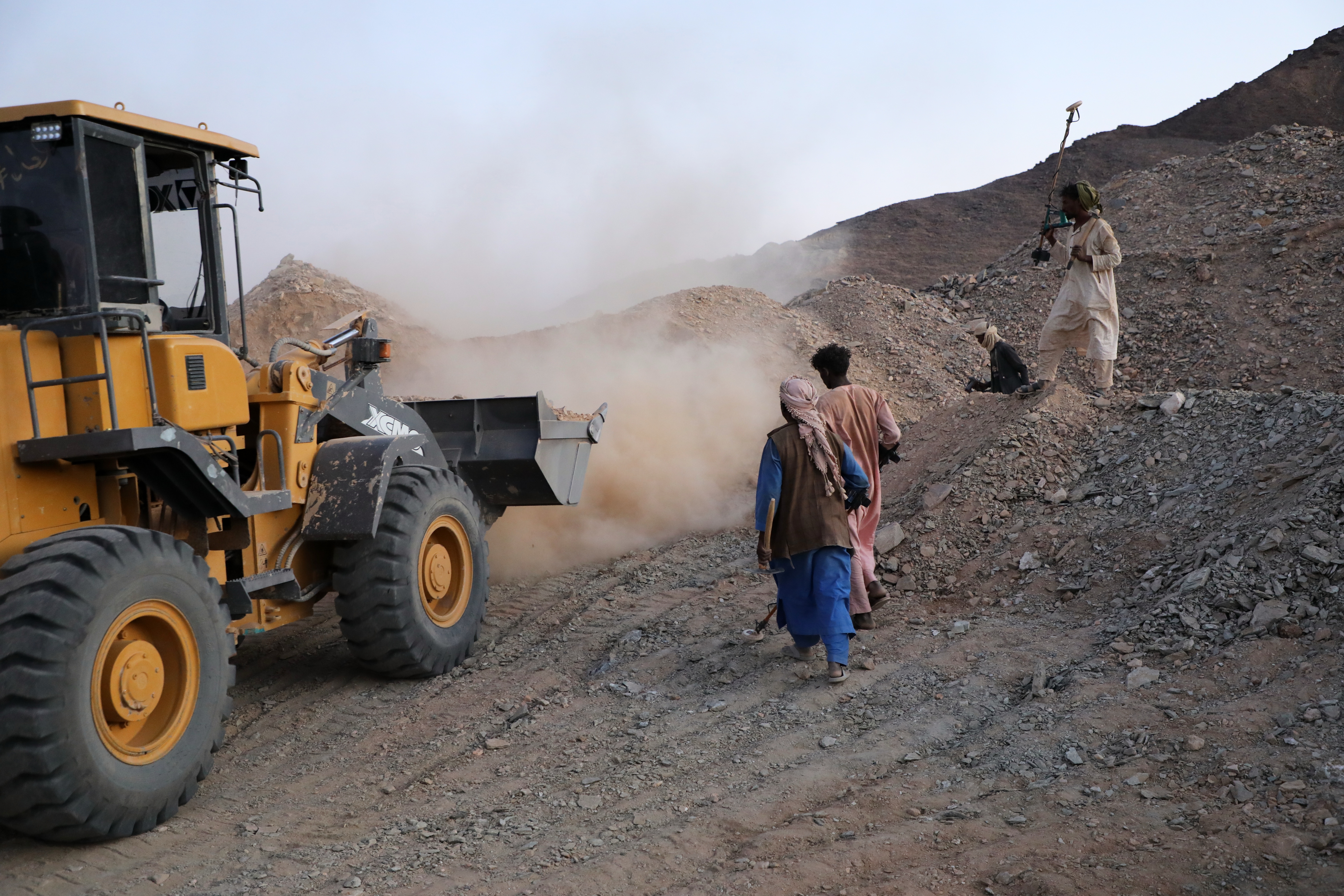 A front-loader loads dirt and crushed rock into a processing machine.